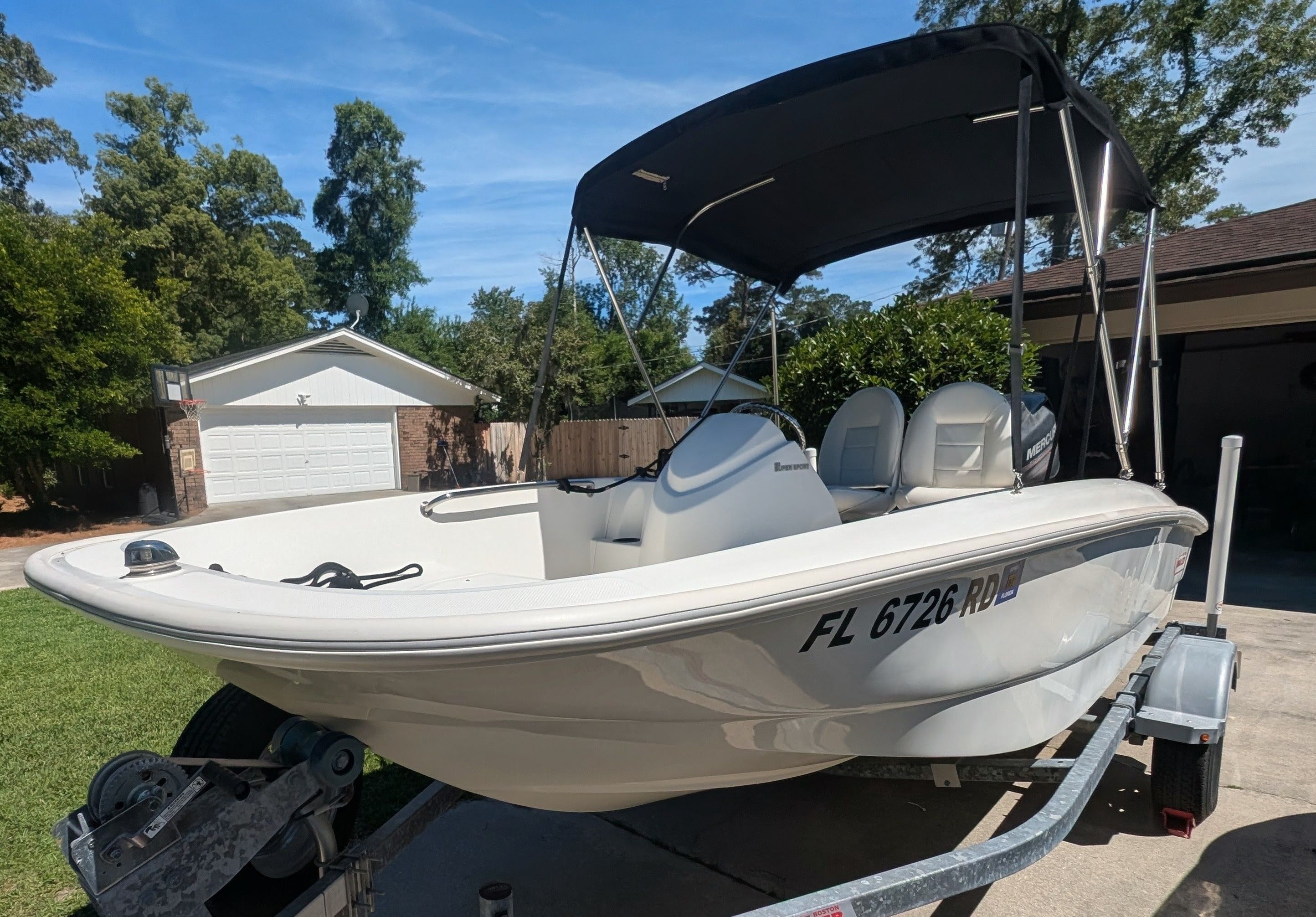 A 2016 Boston Whaler 150 Super Sport on a trailer in a yard.