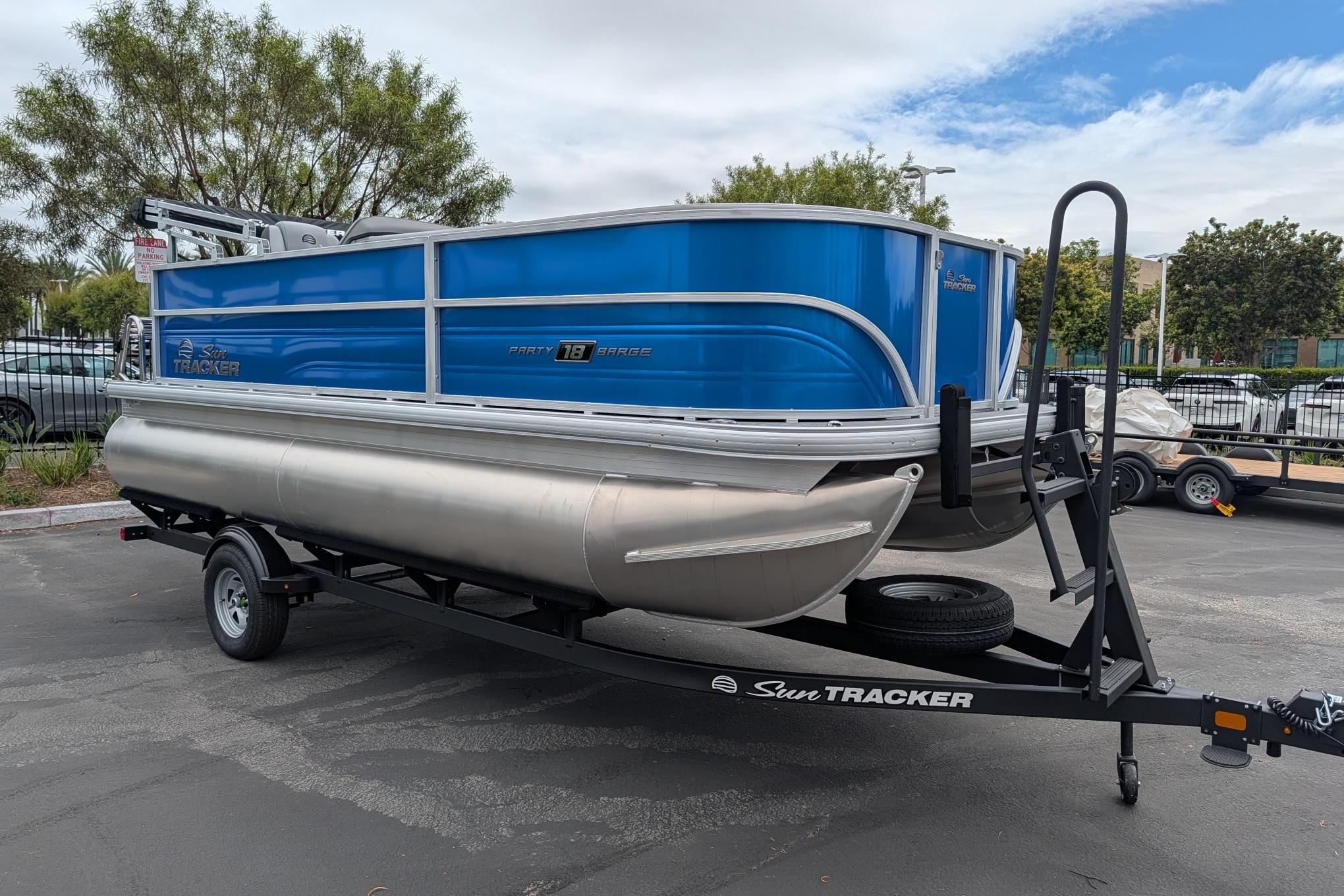 2026 Sun Tracker Party Barge 18 DLX pontoon boat on trailer, parked outdoors.