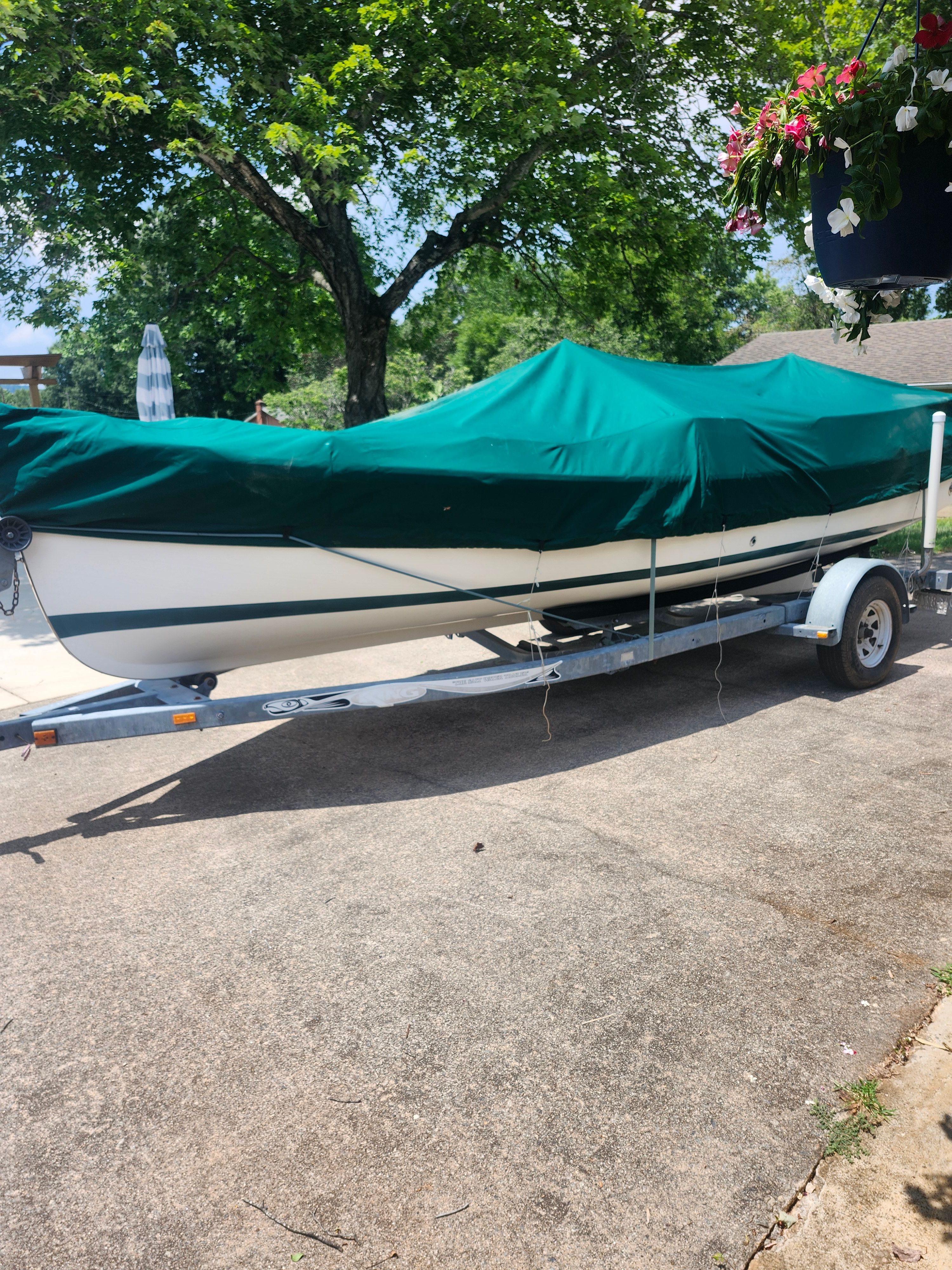 A 2000 Ranger Tugs Martini 21 Launch on a trailer, covered with a green tarp.