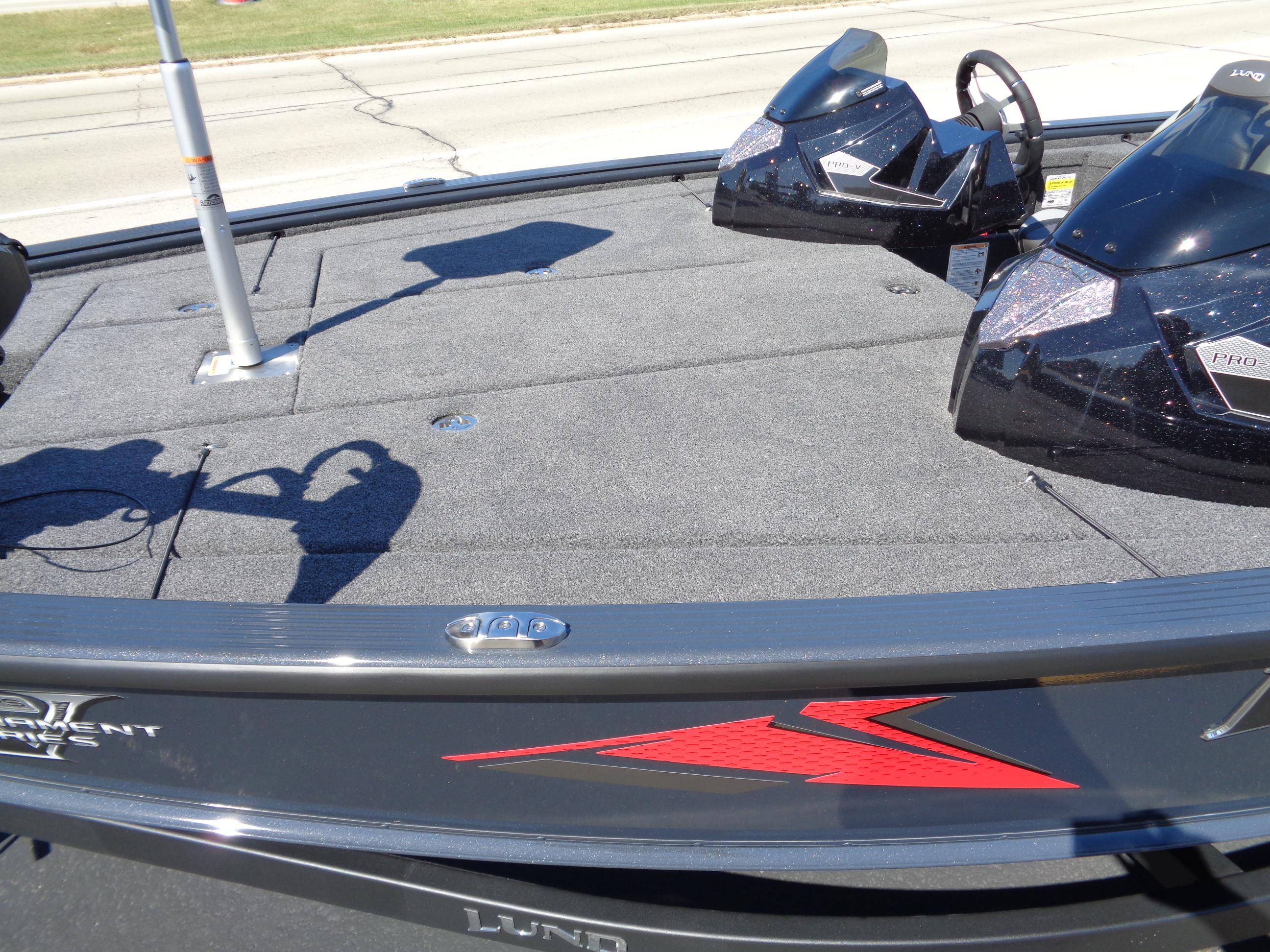 2025 Lund 1875 Pro-V Bass XS boat deck with steering consoles and carpeted surface.