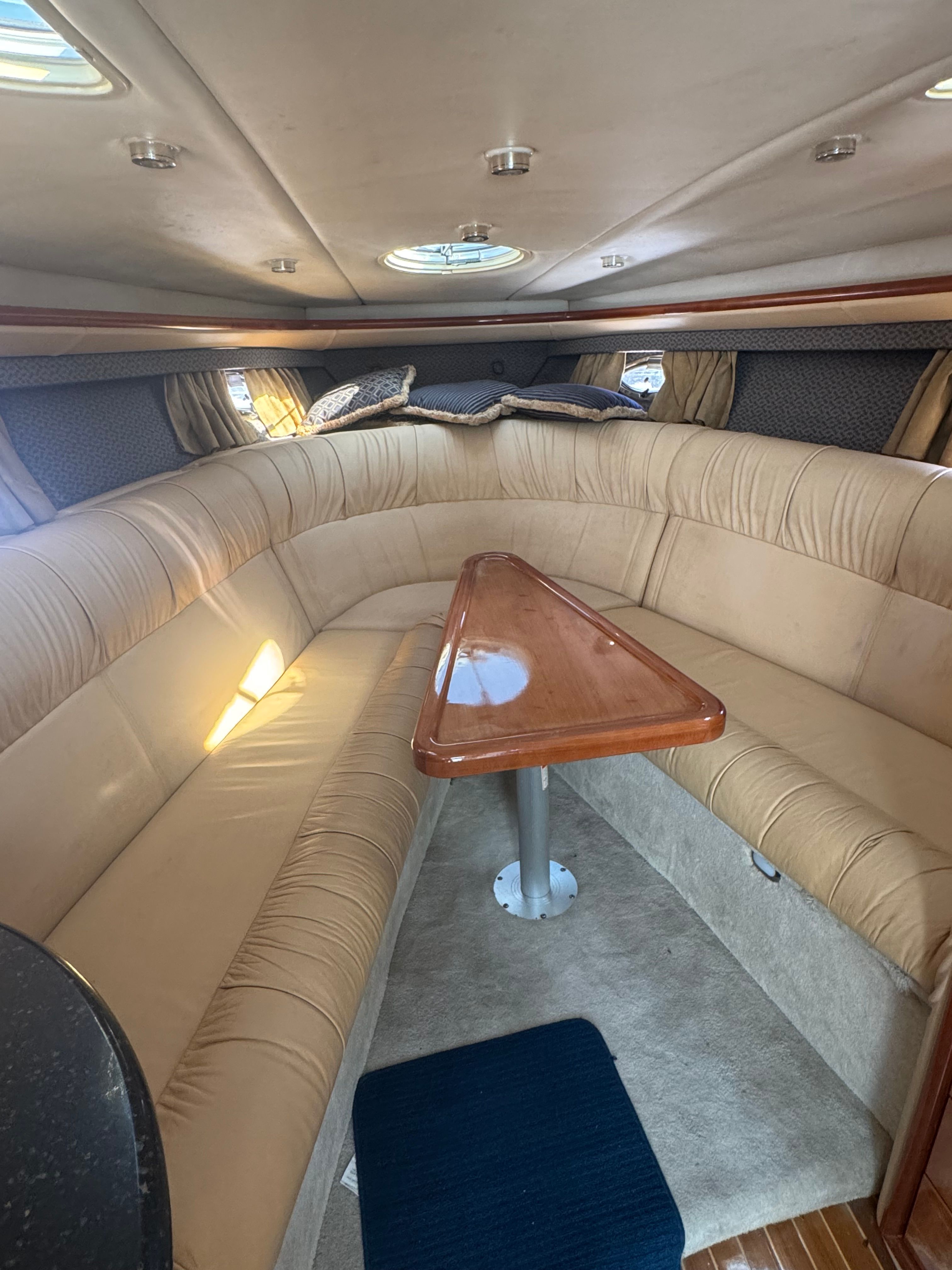Interior of a 2003 Cobalt 360 with beige sofa and wooden table.