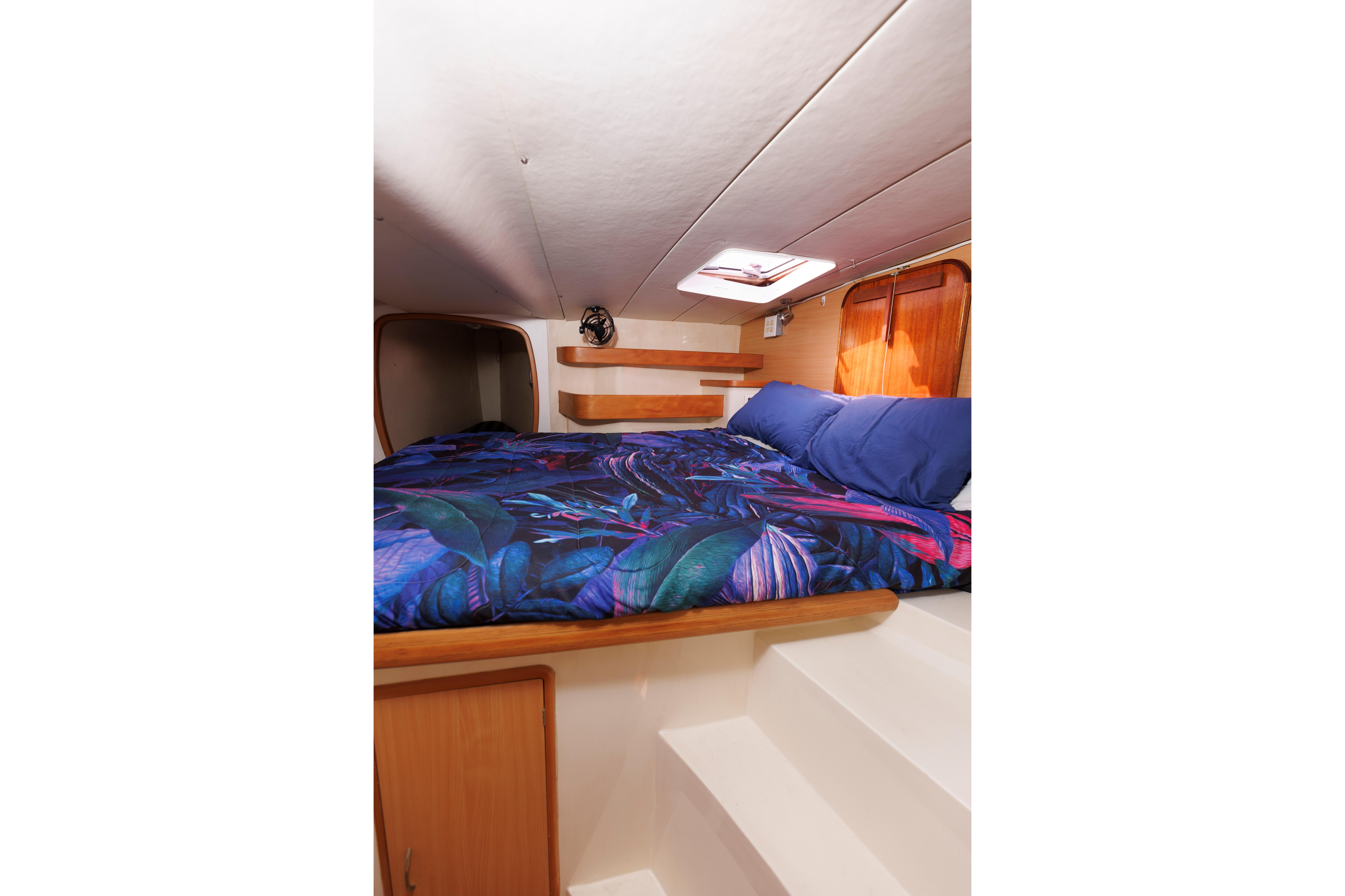 Cozy cabin interior of 2006 Leopard 43 yacht with vibrant bedding and wooden accents.