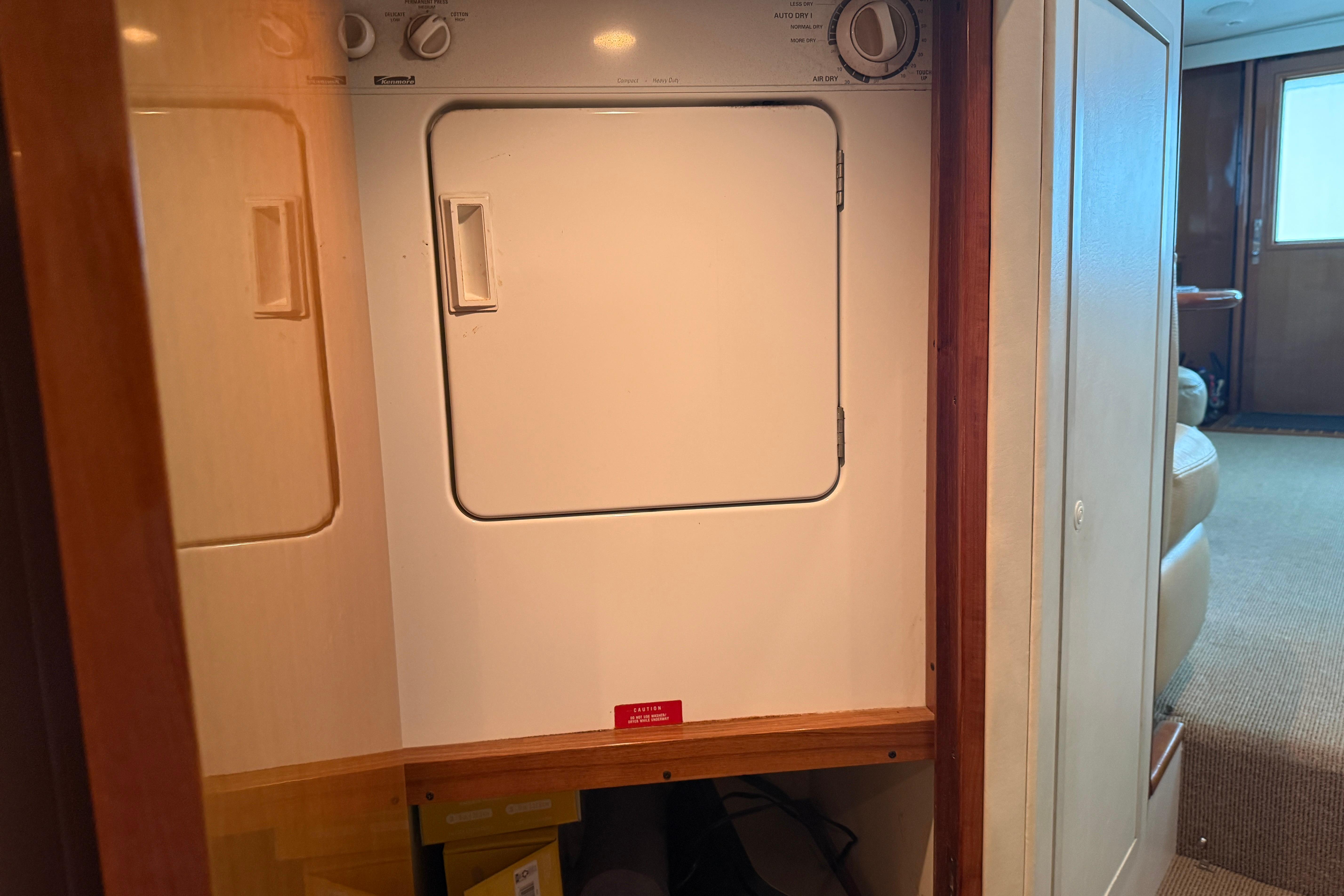 Laundry area inside a 2000 Viking 55 Convertible yacht, featuring a compact dryer.