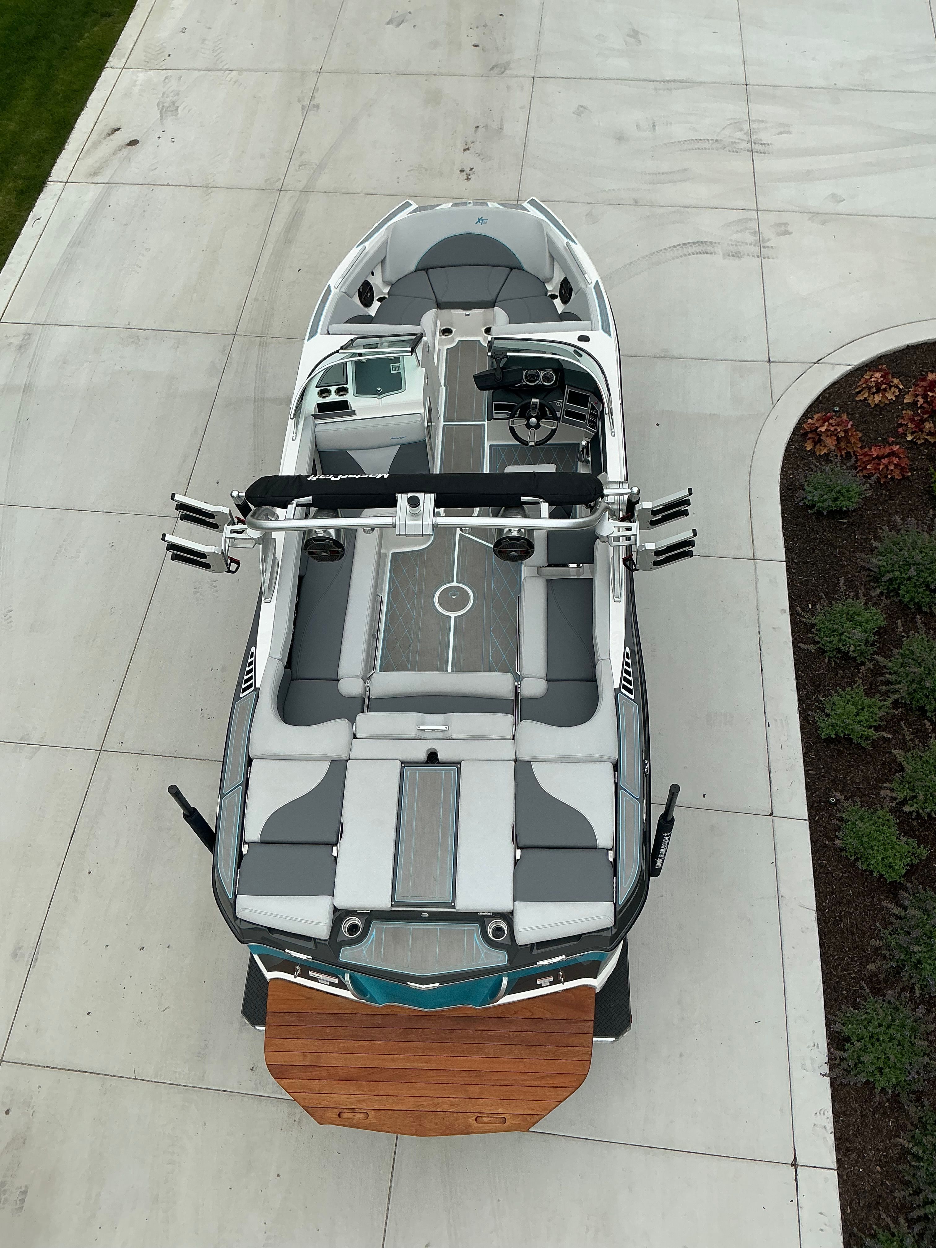 Aerial view of a MasterCraft XT22 boat on a concrete lot, featuring gray and white upholstery.