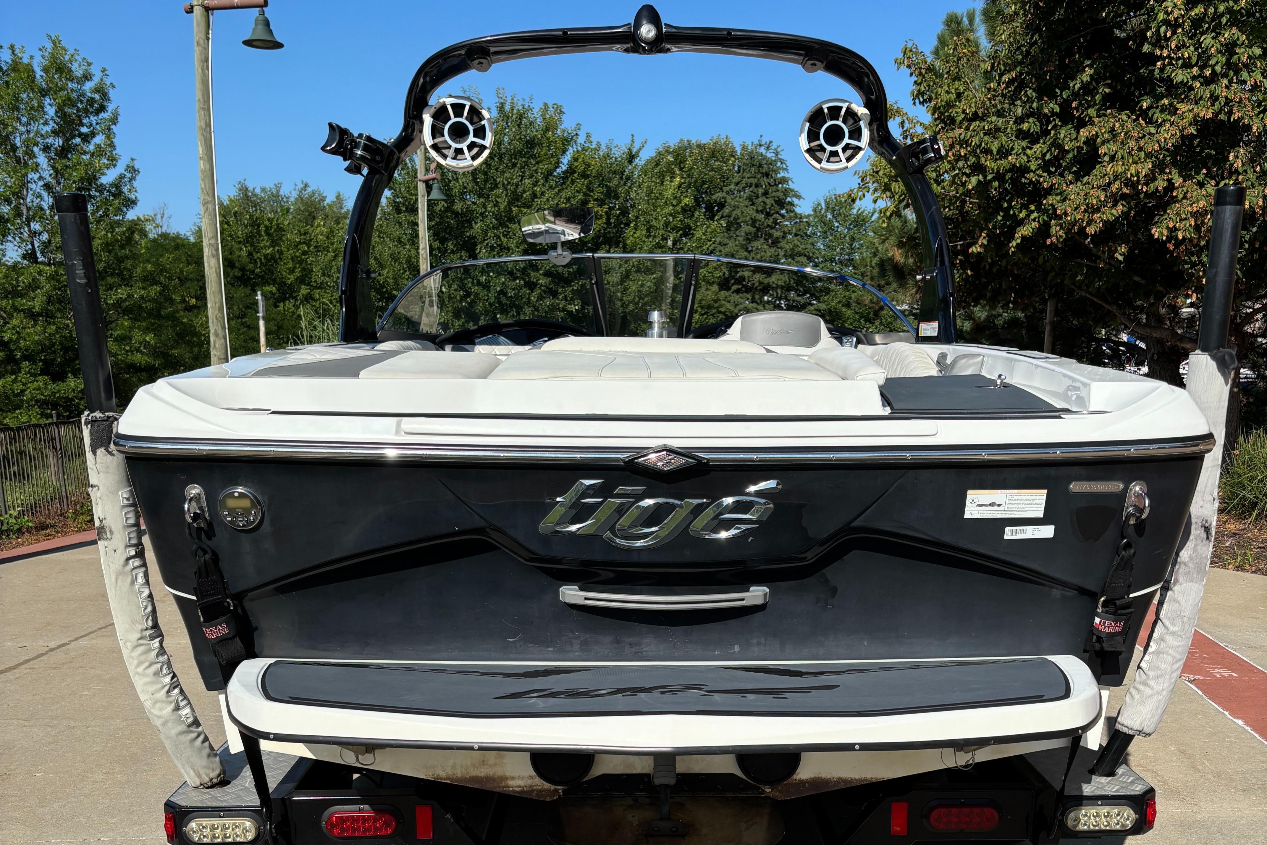 2014 Tigé RZR boat, rear view, parked outdoors with trees in the background.