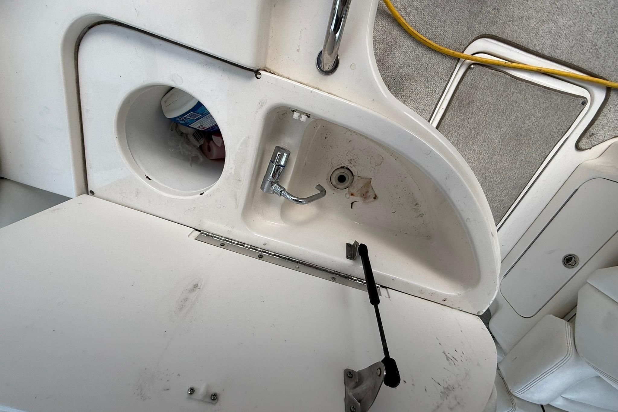 2005 Sea Ray 290 SLX boat sink area with storage compartment and faucet.