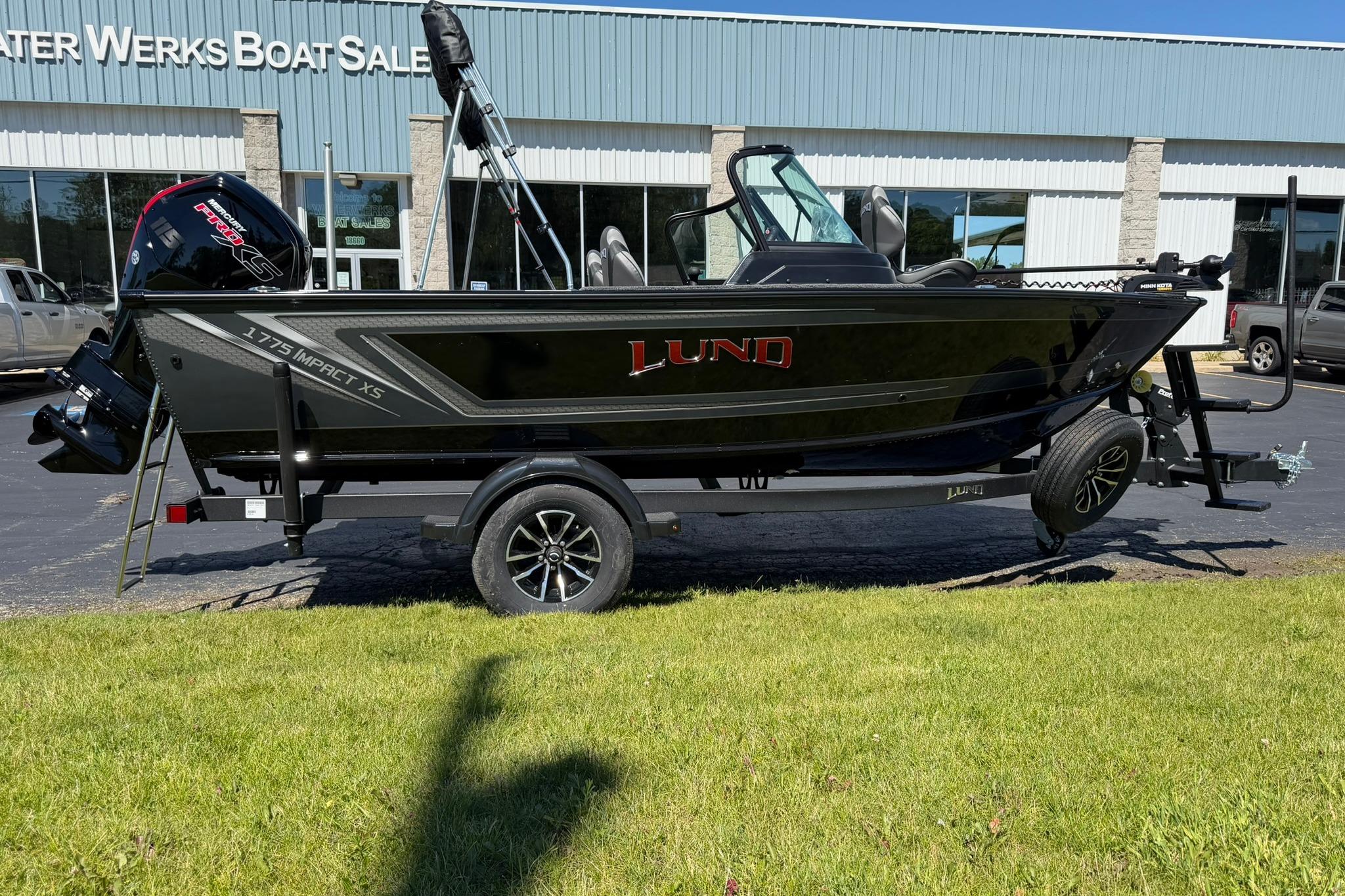 2027 Lund 1775 Impact XS Sport boat on trailer outside dealership.