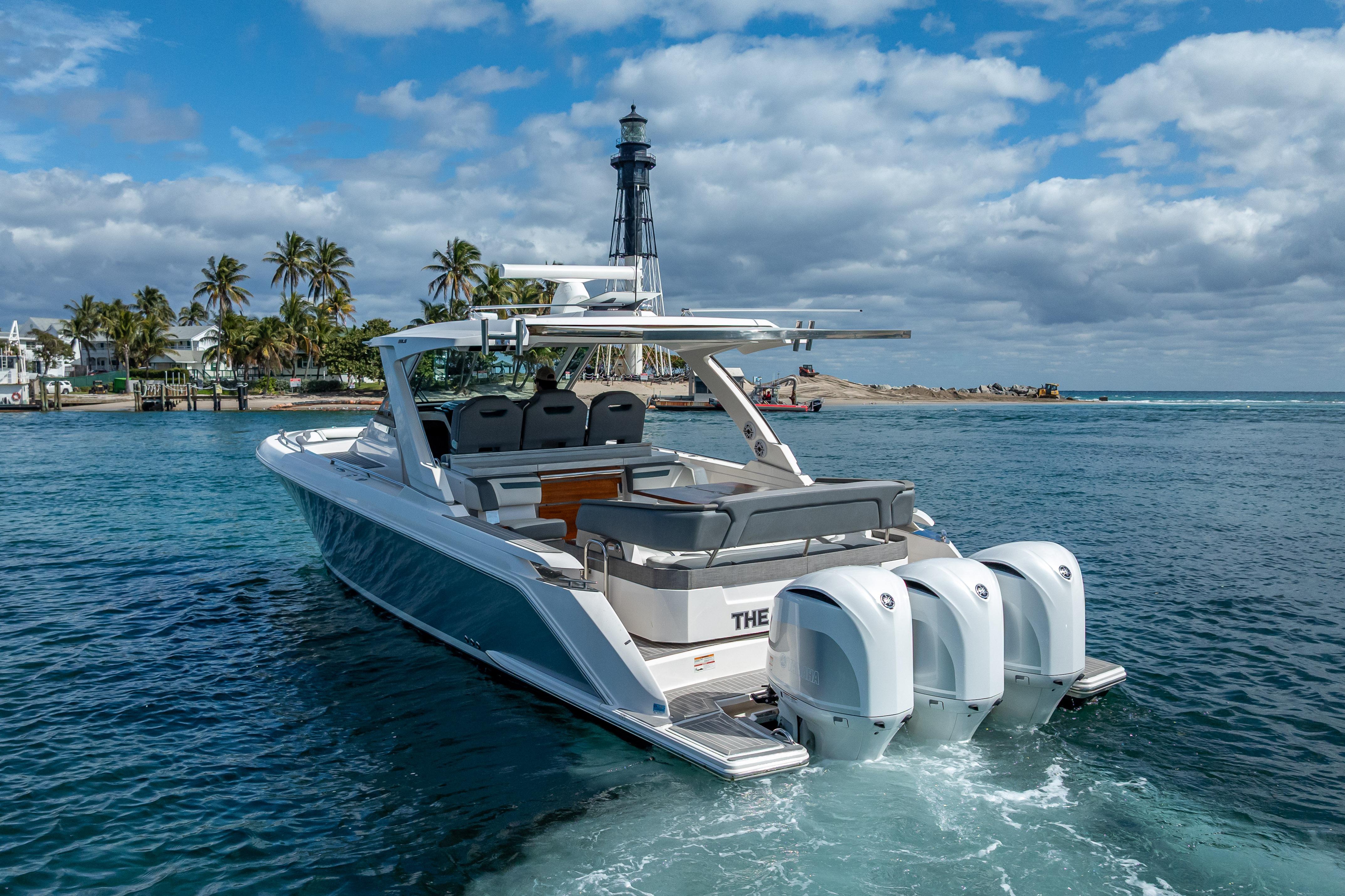 2019 Tiara Sport 38 LS boat cruising near a lighthouse and palm trees.
