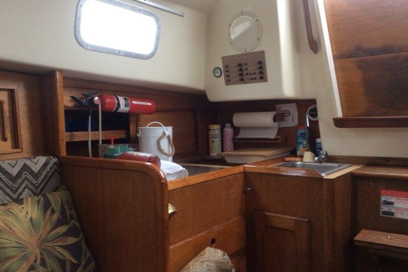 Interior of a 1980 Sloop 27.7 Bristol sailboat with wooden cabinetry and kitchen essentials.