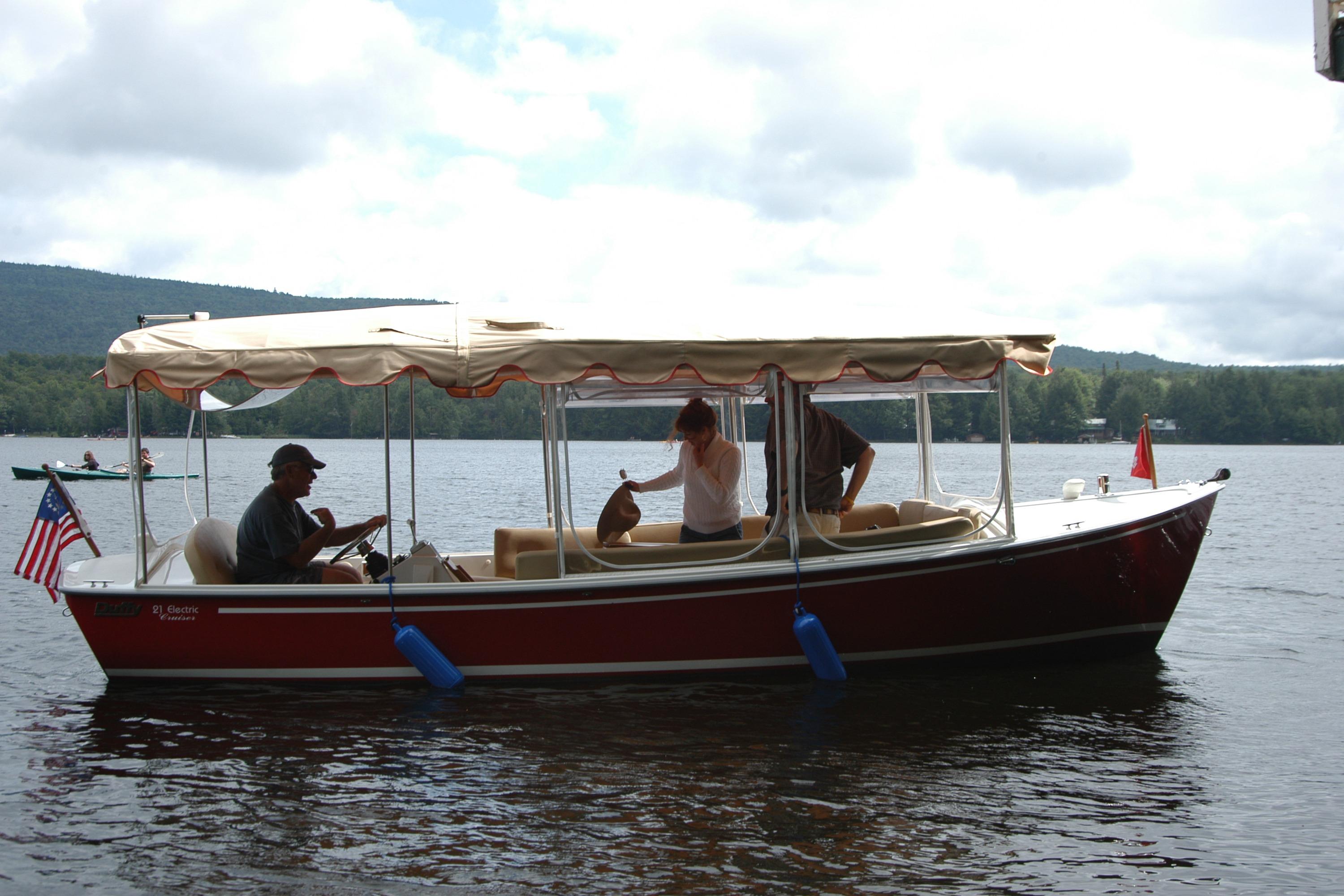 2004 Duffy 21 Classic boat on a lake with passengers under a canopy.