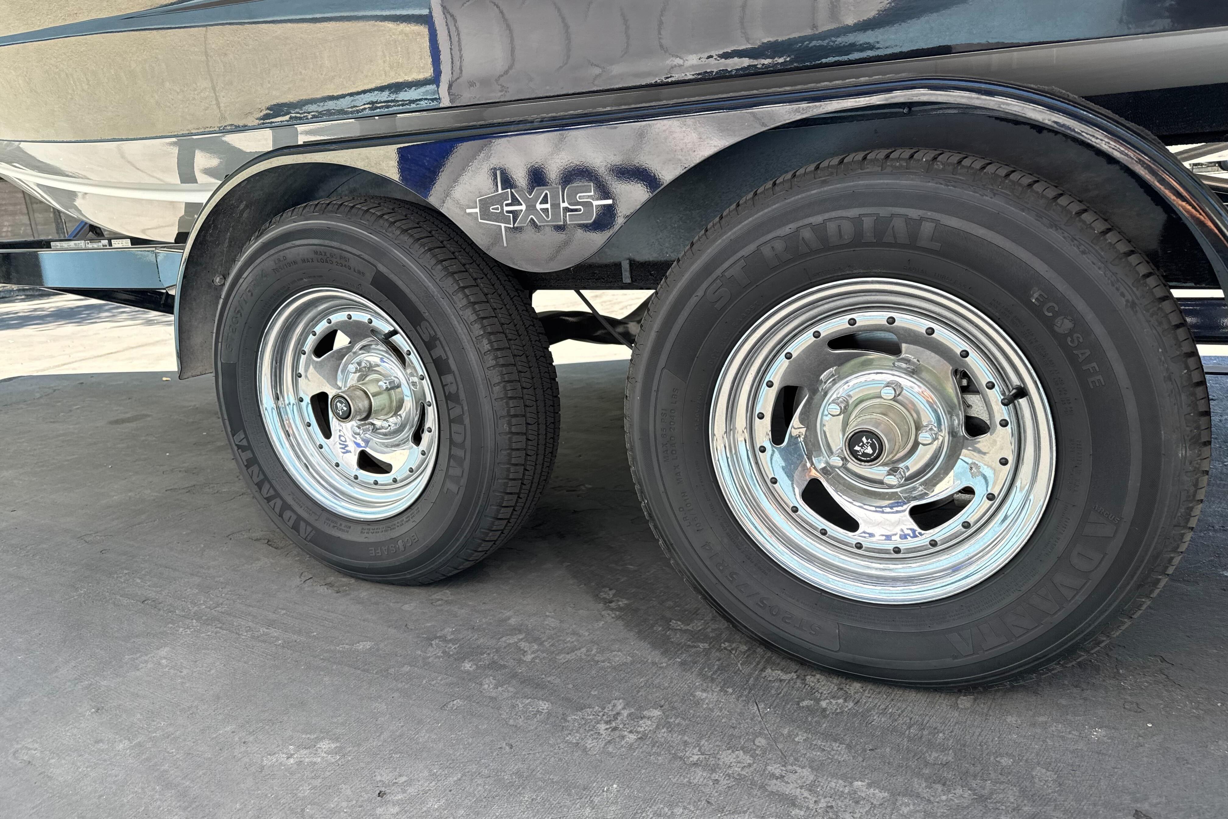 Trailer wheels of a 2015 Axis A20 boat on a concrete surface.