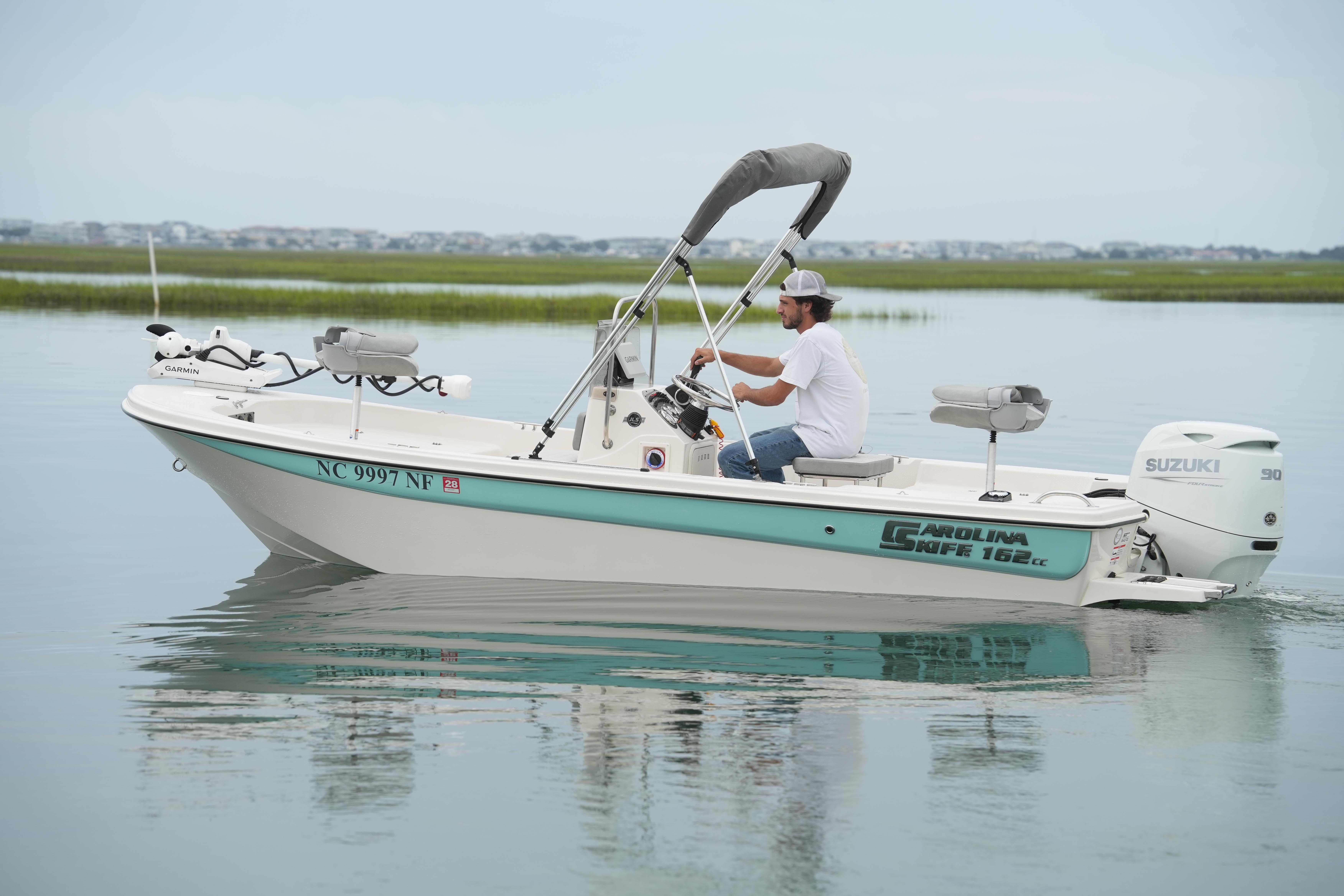 2025 Carolina Skiff 162 JLS boat cruising on calm water with Suzuki outboard motor.