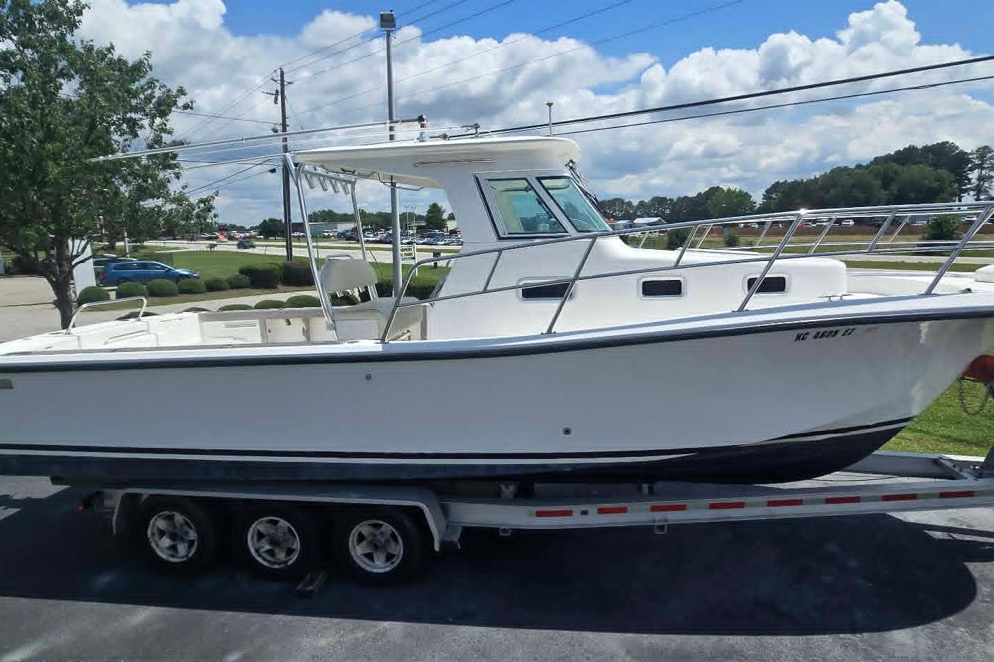2003 True World Marine 286 boat on trailer, parked outdoors under a cloudy sky.
