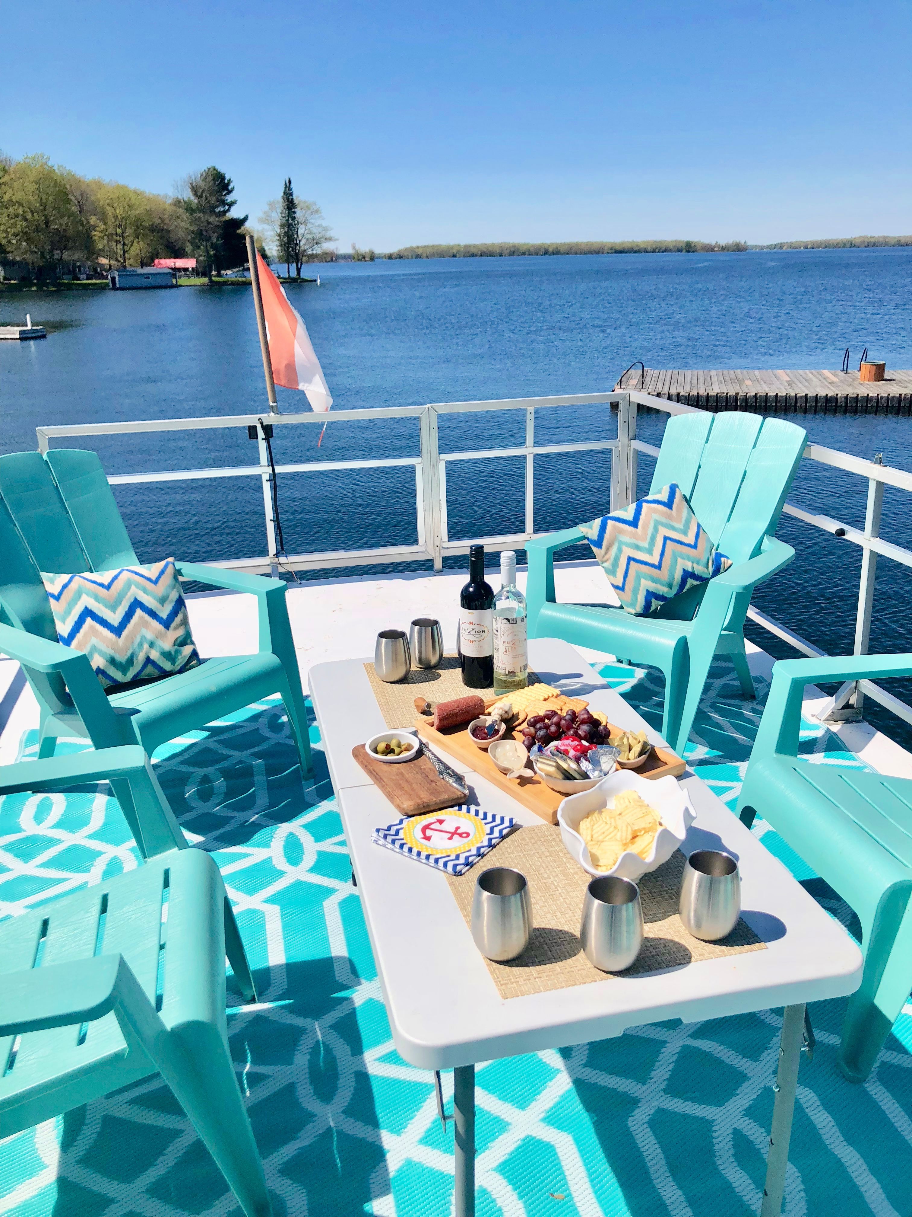 A cozy deck with turquoise chairs and a table filled with snacks and drinks.