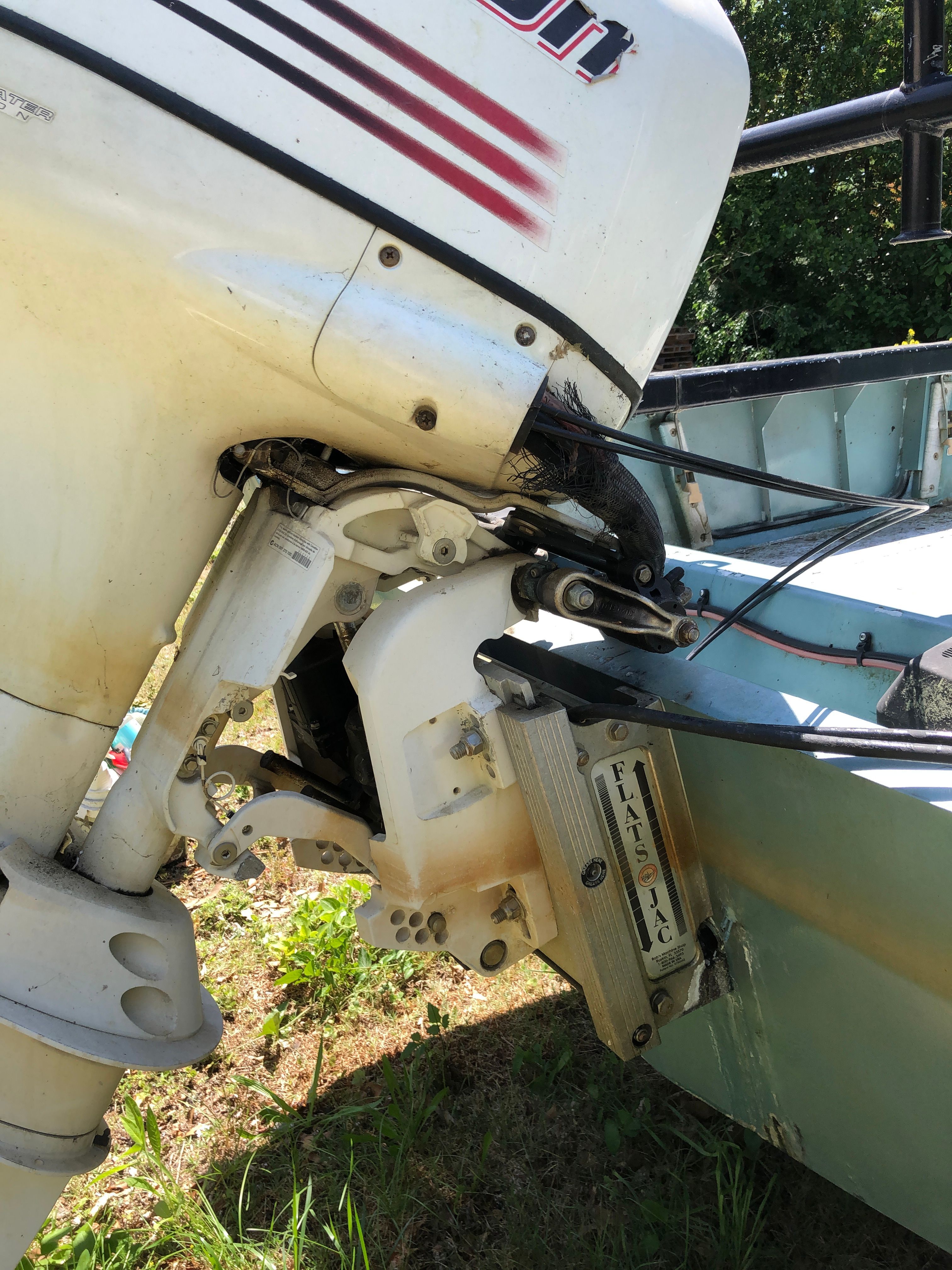 An outboard motor is mounted on a 1991 Boston Whaler Guardian, resting on grass.