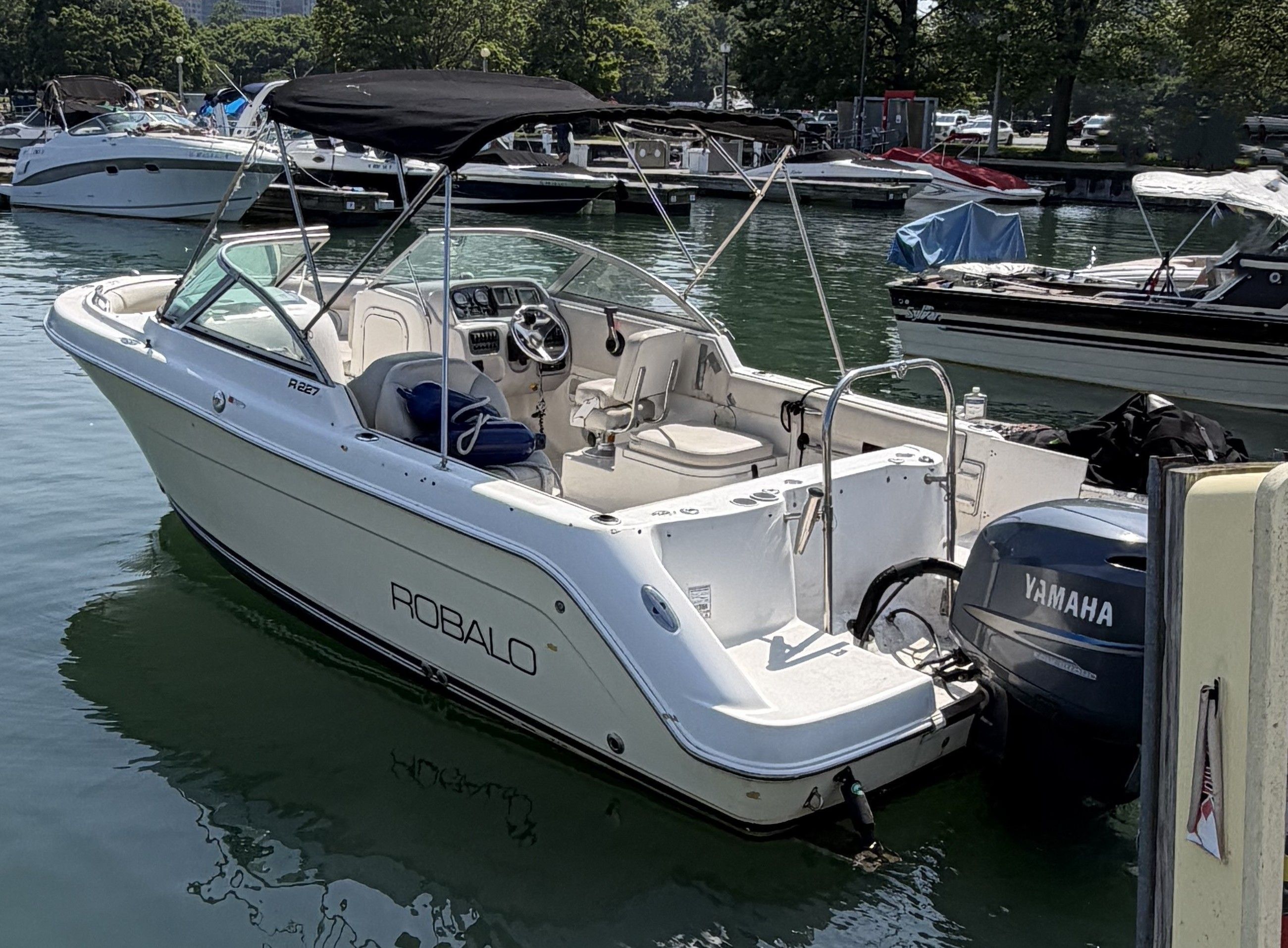 A 2005 Robalo R227 Dual Console boat is on the water, surrounded by other boats.