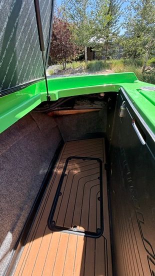 Green storage area in the boat with wooden floor and gray walls.