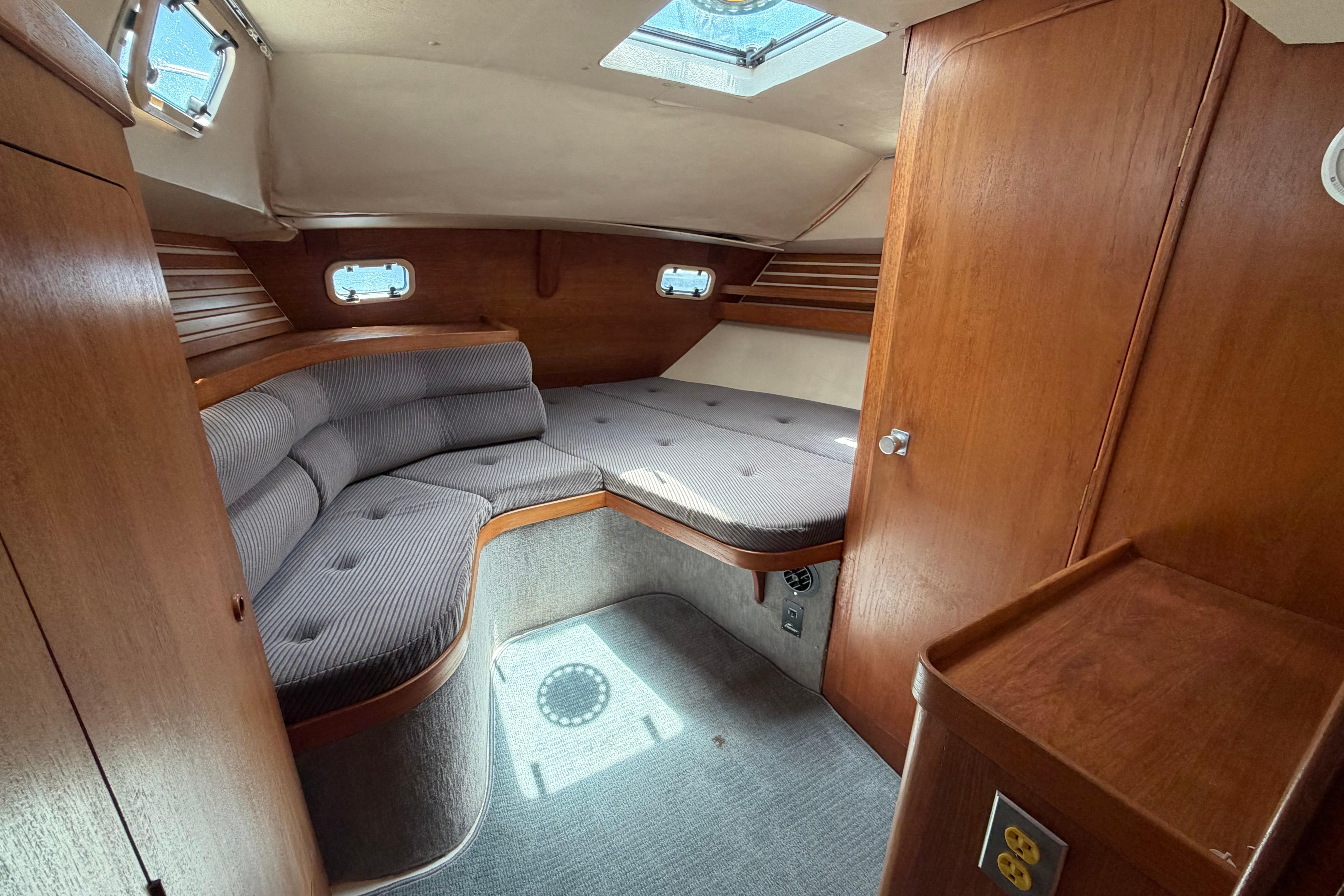 Cozy cabin interior of 1987 Moody 376 sailboat with wooden finish and cushioned seating.