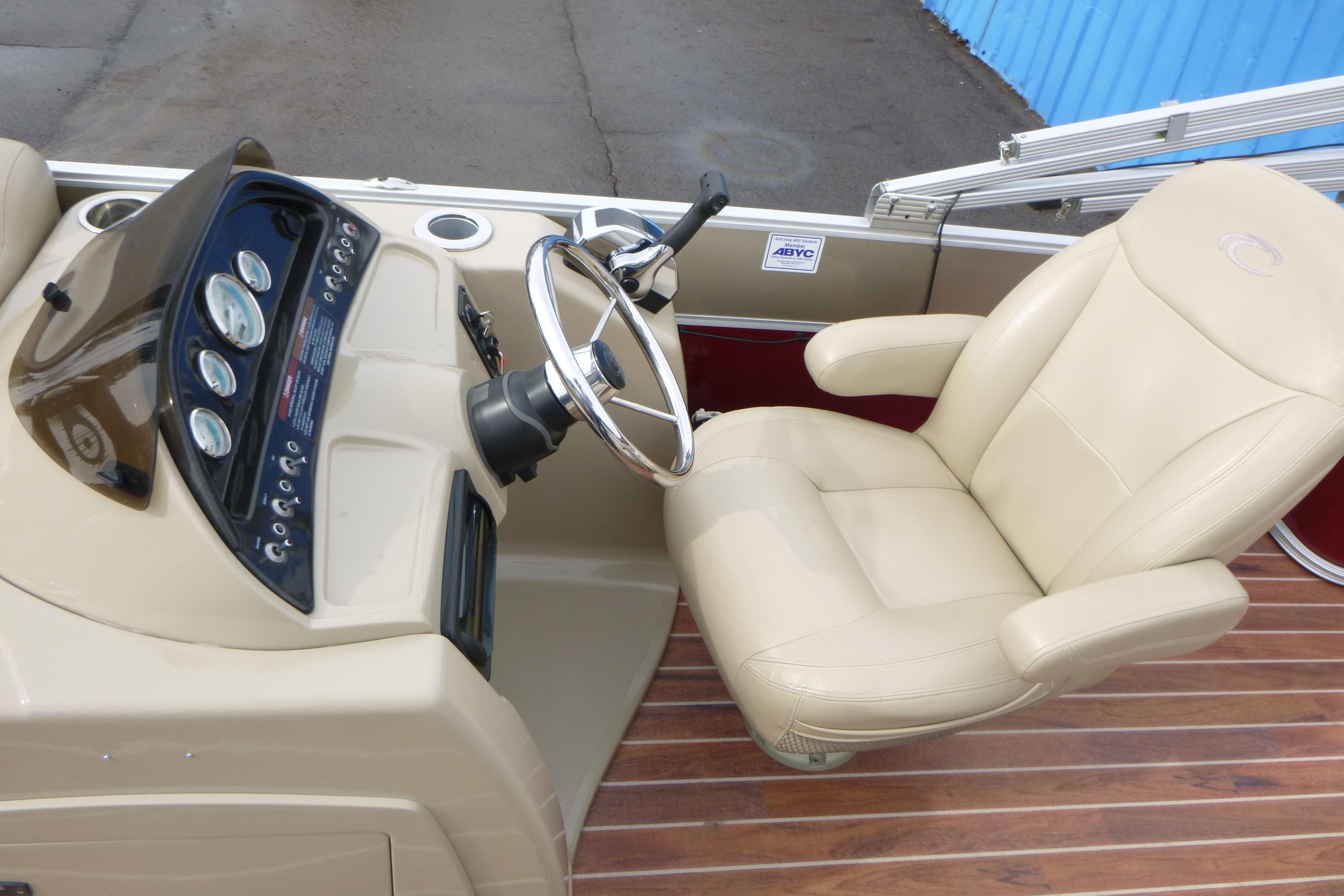 Steering console of 2012 Crest 230SLR Classic boat with beige captain's chair.