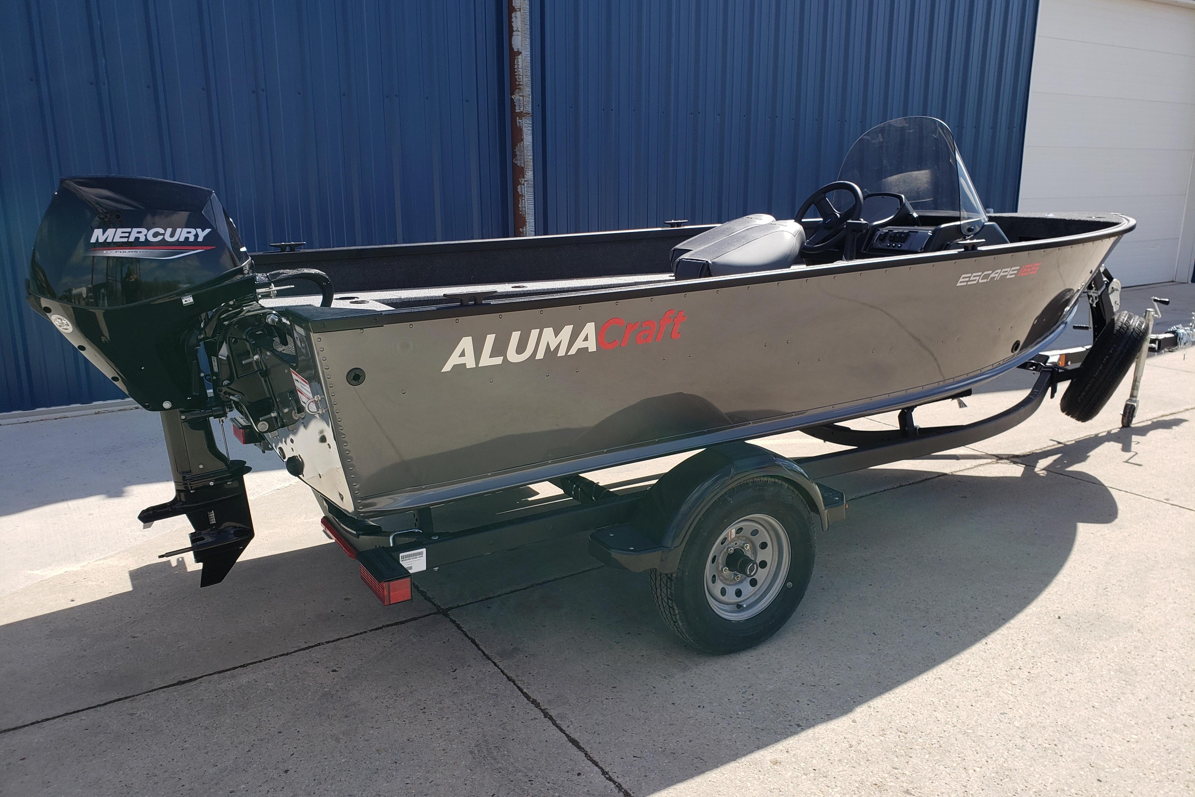 2026 Alumacraft Escape 165 CS boat with Mercury engine on trailer, parked outdoors.