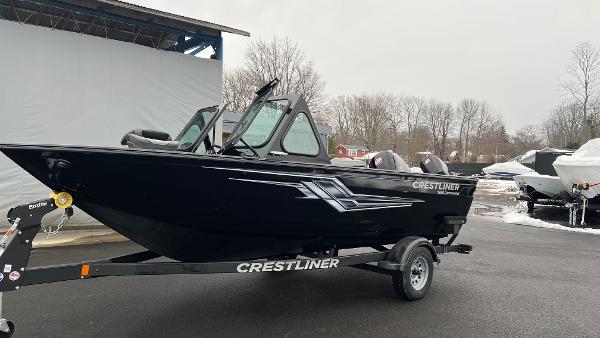 2025 Crestliner 1850 Commander boat on trailer, black exterior, parked outdoors.