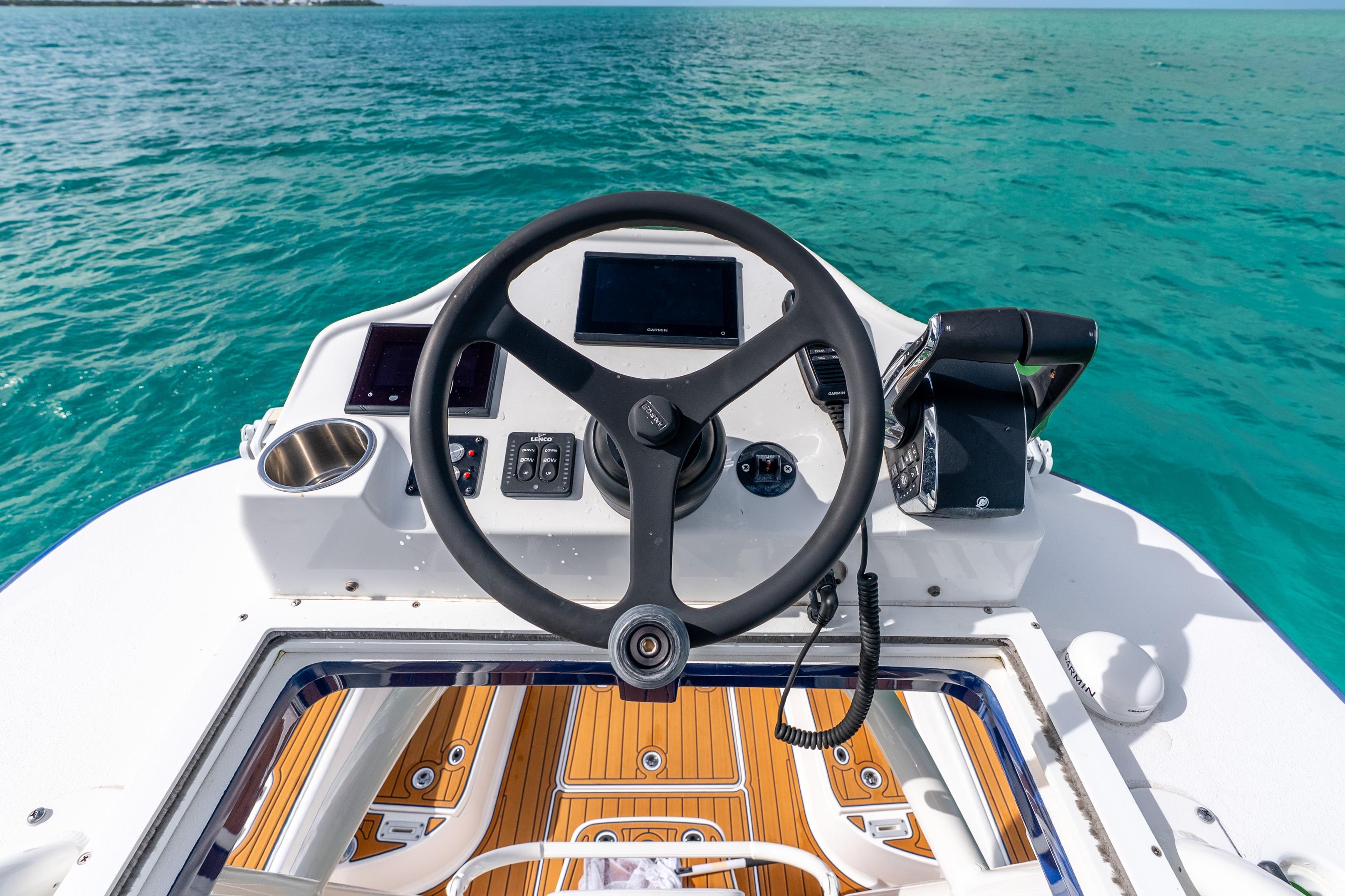 2024 Caymas 281 HB boat helm with ocean view, featuring modern controls and teak flooring.