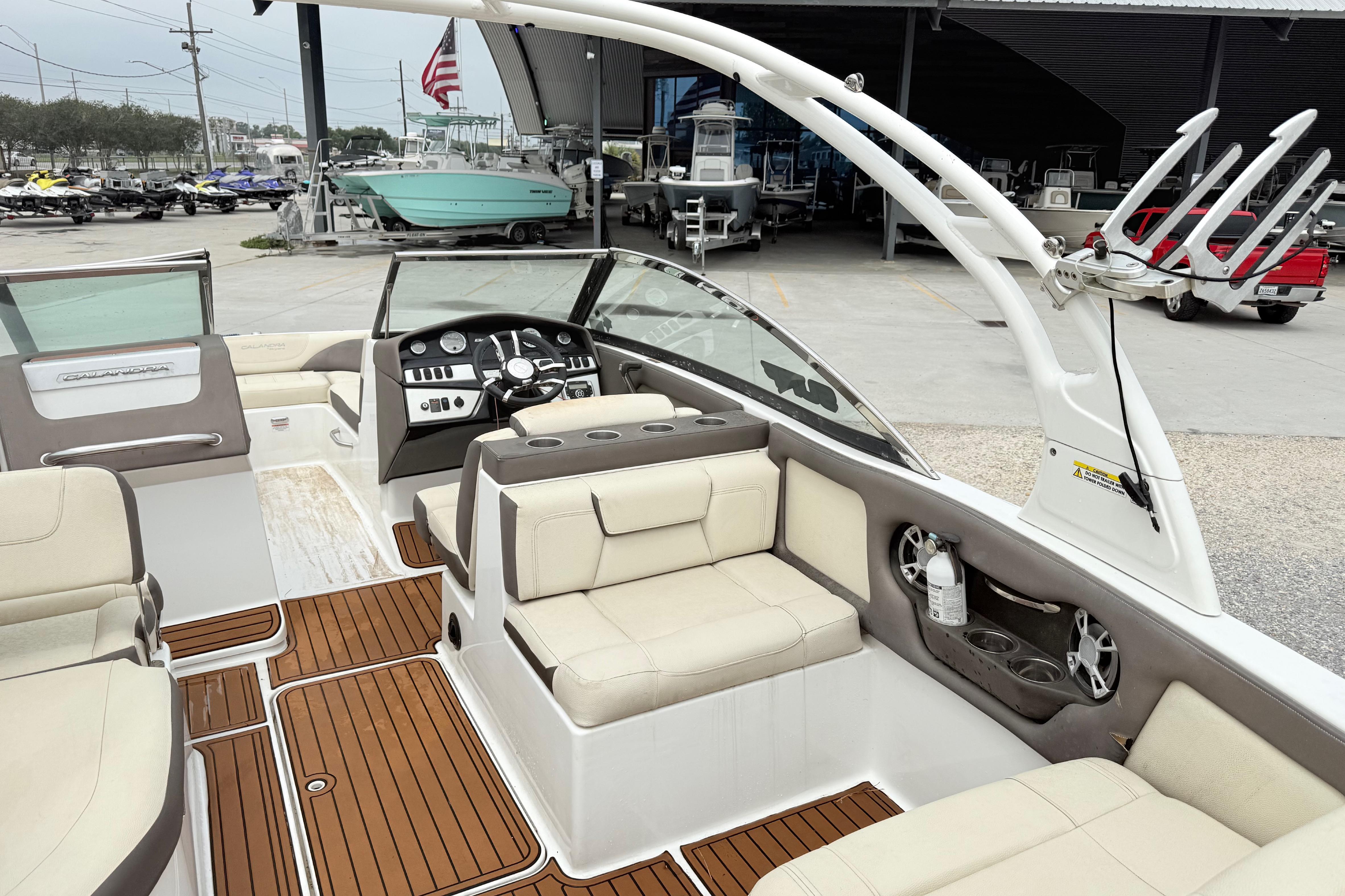 2018 Bryant Calandra boat interior with beige seating and wooden flooring at a marina.