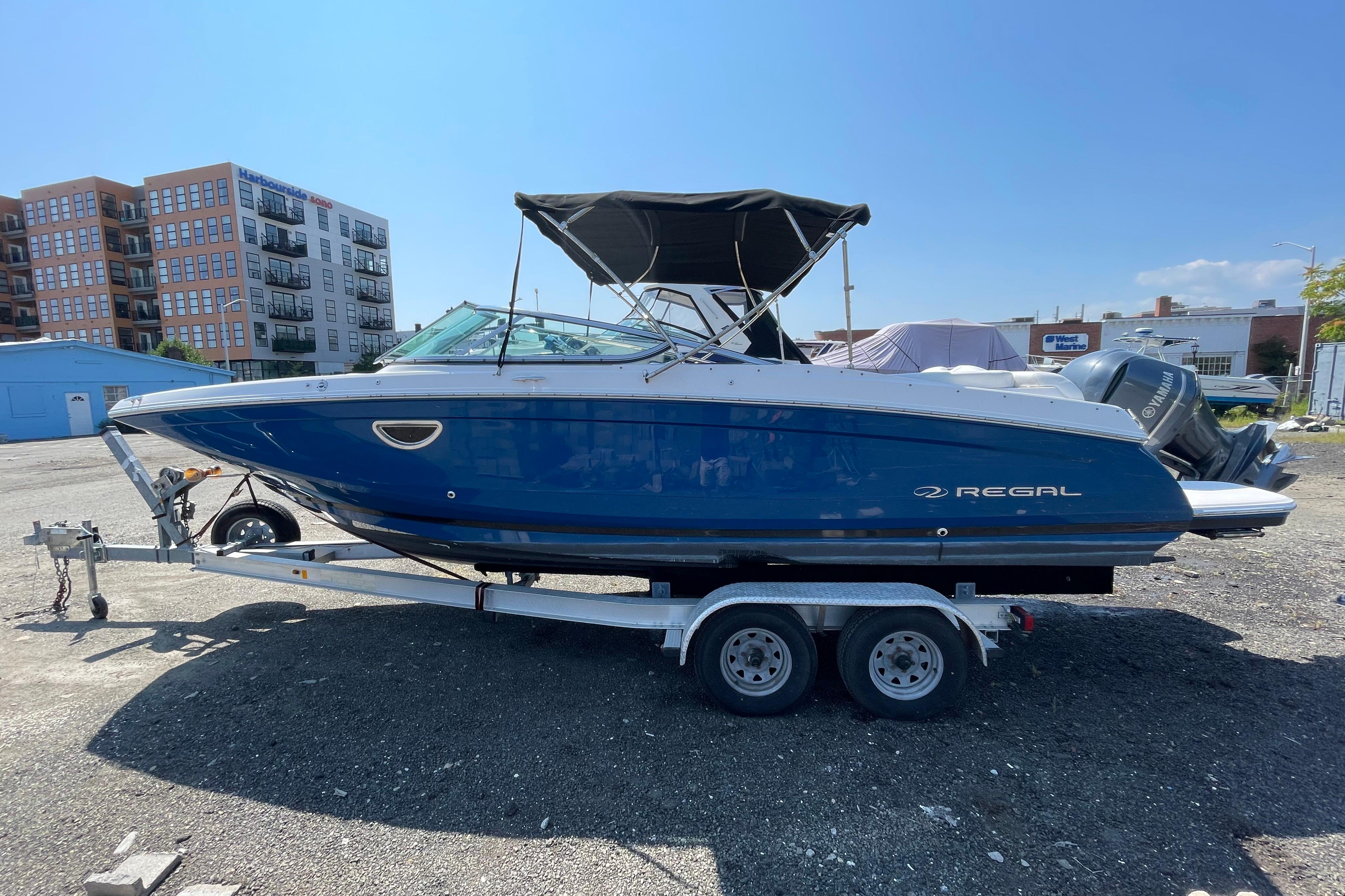 2018 Regal 26 OBX boat on trailer, blue hull, parked outdoors.
