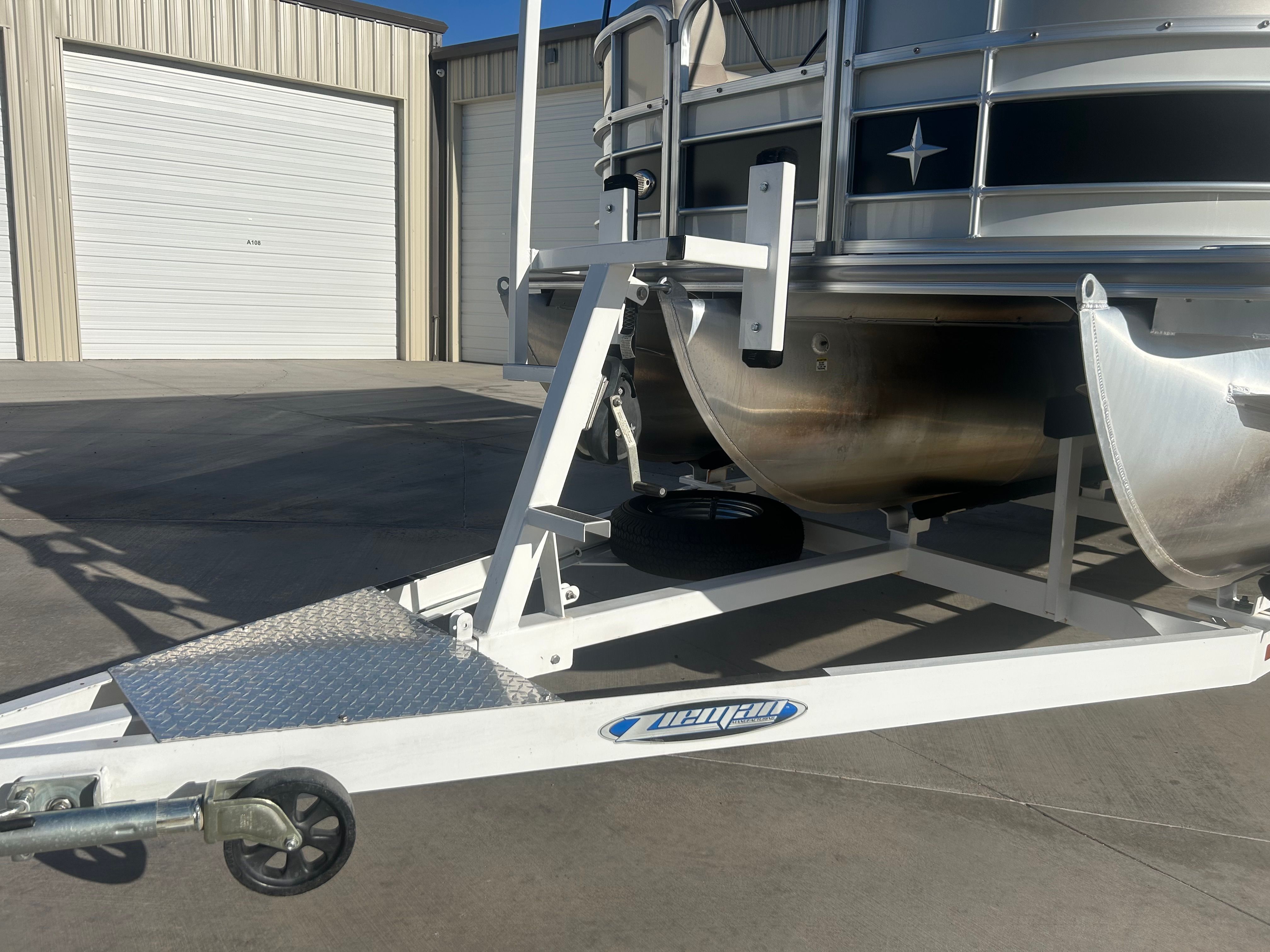 A 2018 Berkshire 24RFX CTS pontoon boat on a white trailer in front of a warehouse.