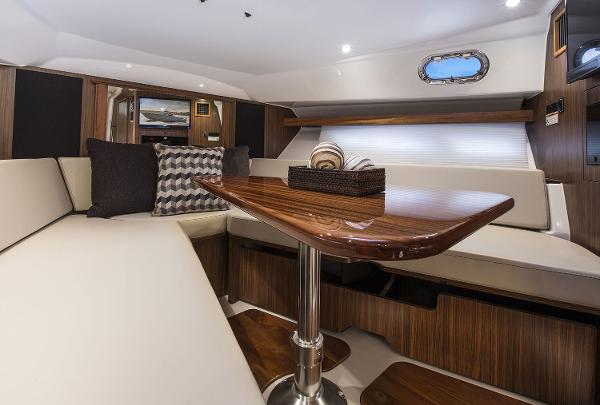 Manufacturer Provided Image: Interior of 2019 Pursuit OS 355 Offshore boat with elegant seating and wooden table.