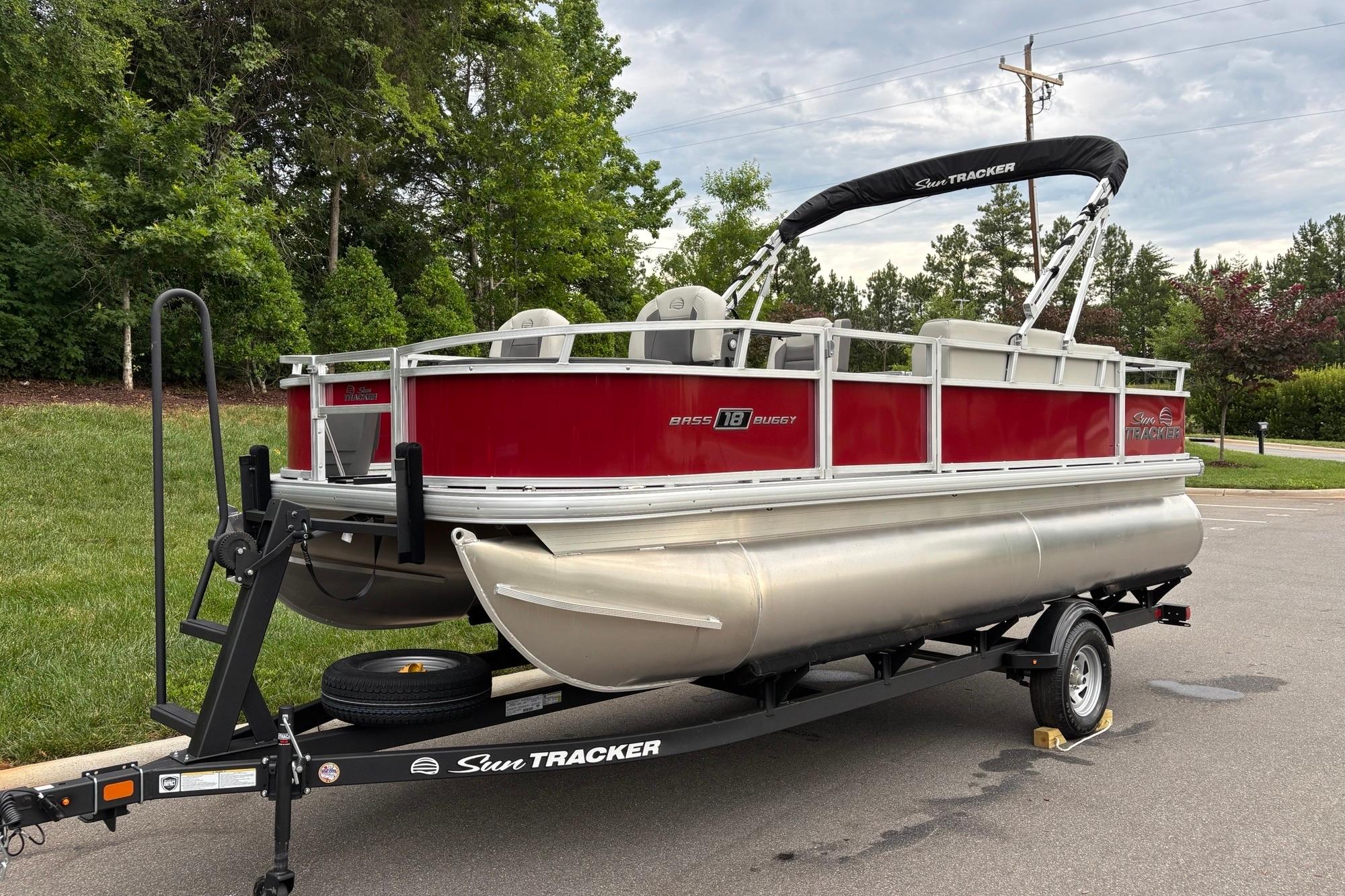 2026 Sun Tracker Bass Buggy 18 DLX pontoon boat on trailer, parked outdoors.