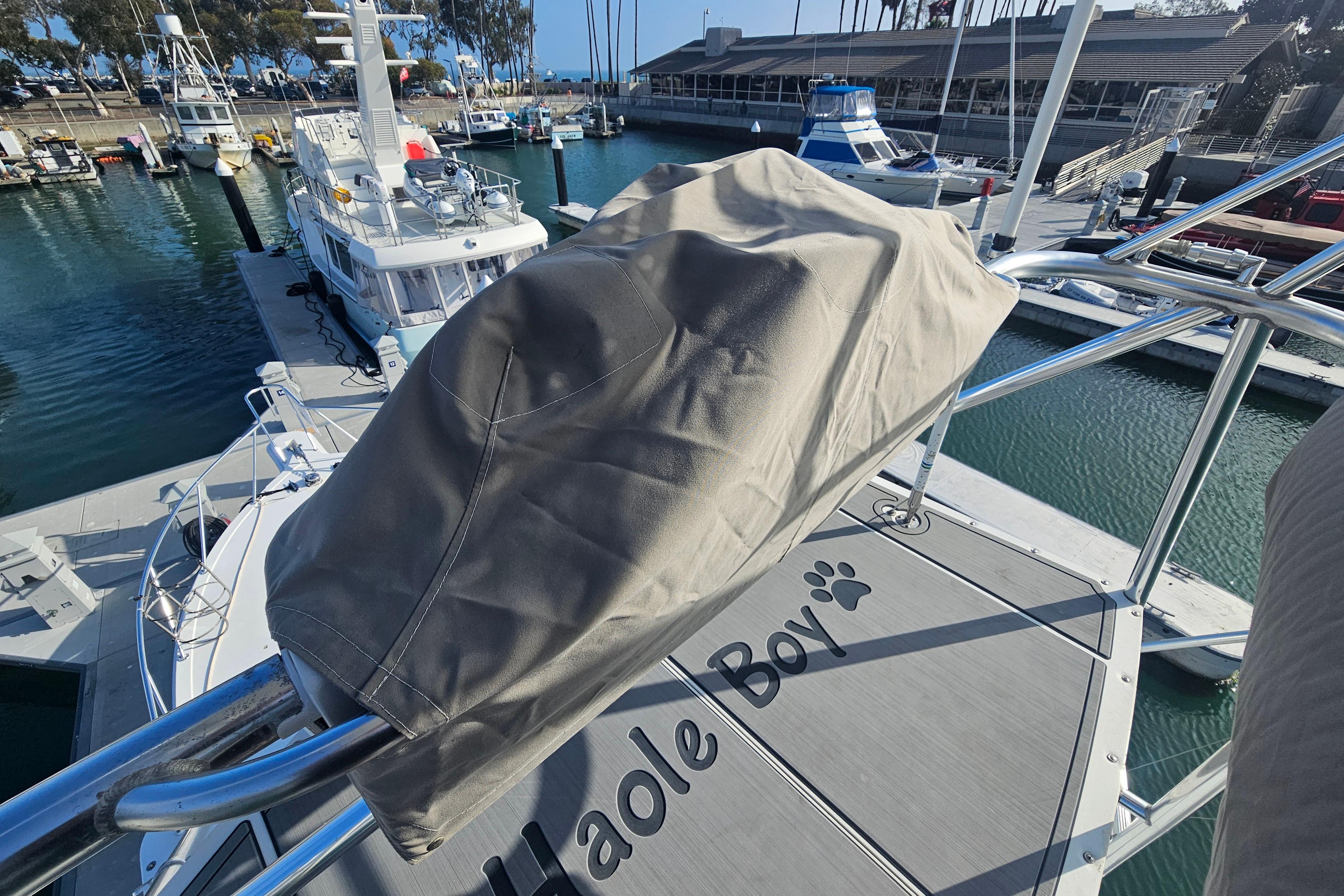 2003 Topaz 32 Express boat docked at marina, covered equipment, "Haole Boy" text on deck.