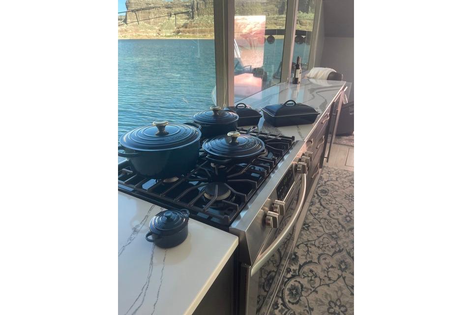 Modern kitchen with cookware on stove, scenic water view through large window, Adonia The Queen Elizabeth 2021.