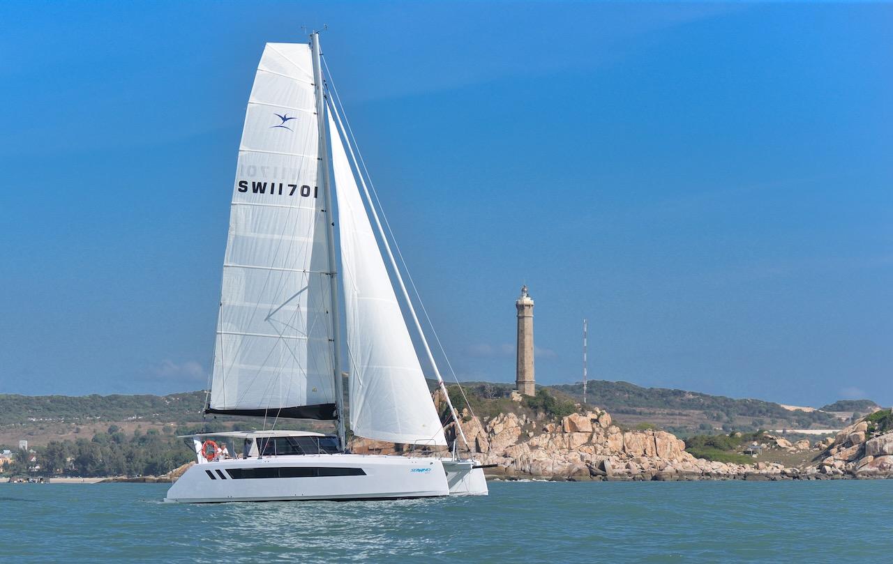 2025 Seawind 1170 catamaran sailing near a coastal lighthouse.