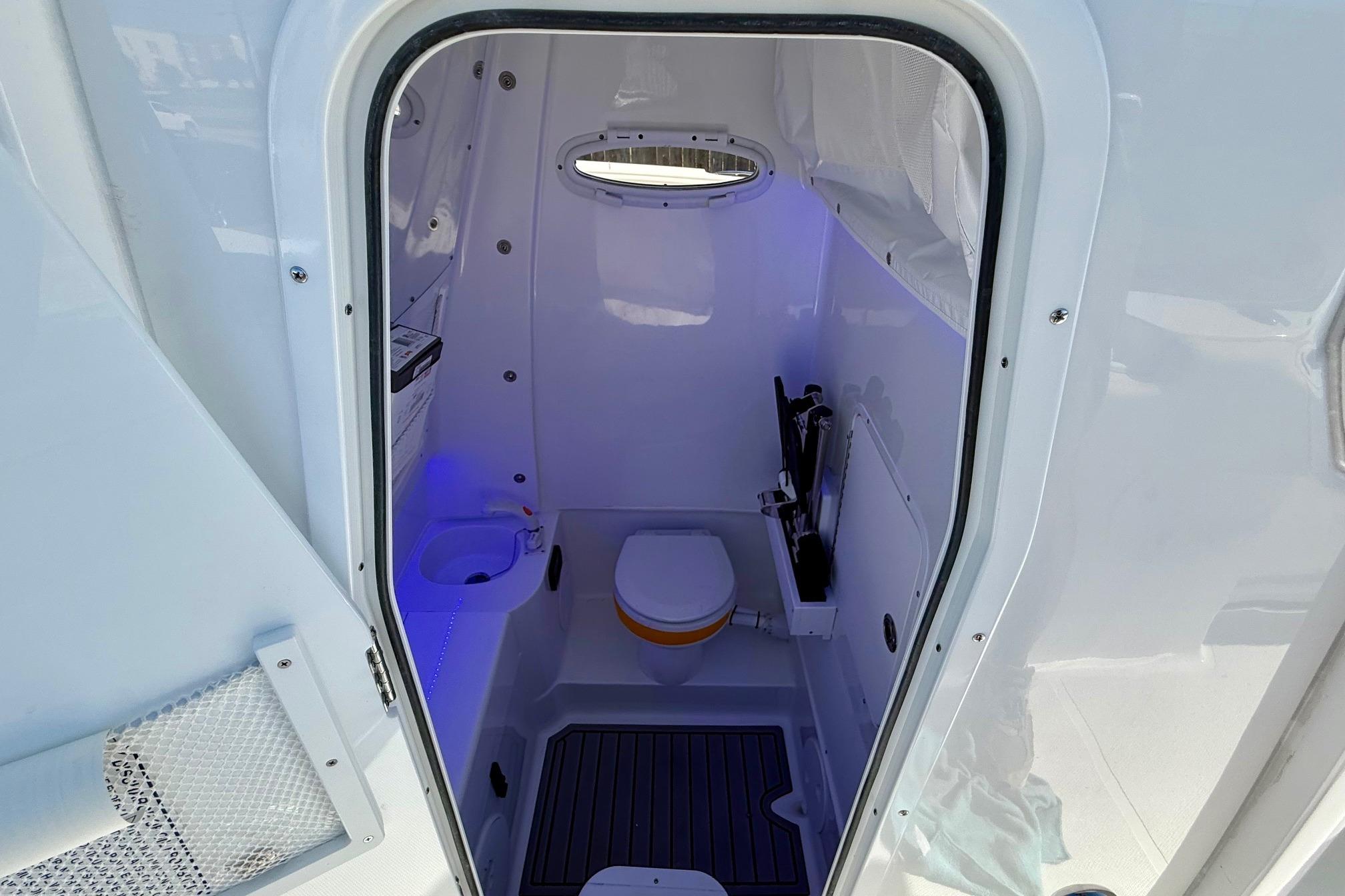 Interior of 2026 Sea Hunt Gamefish 30 Coffin Box boat, featuring a compact marine toilet.