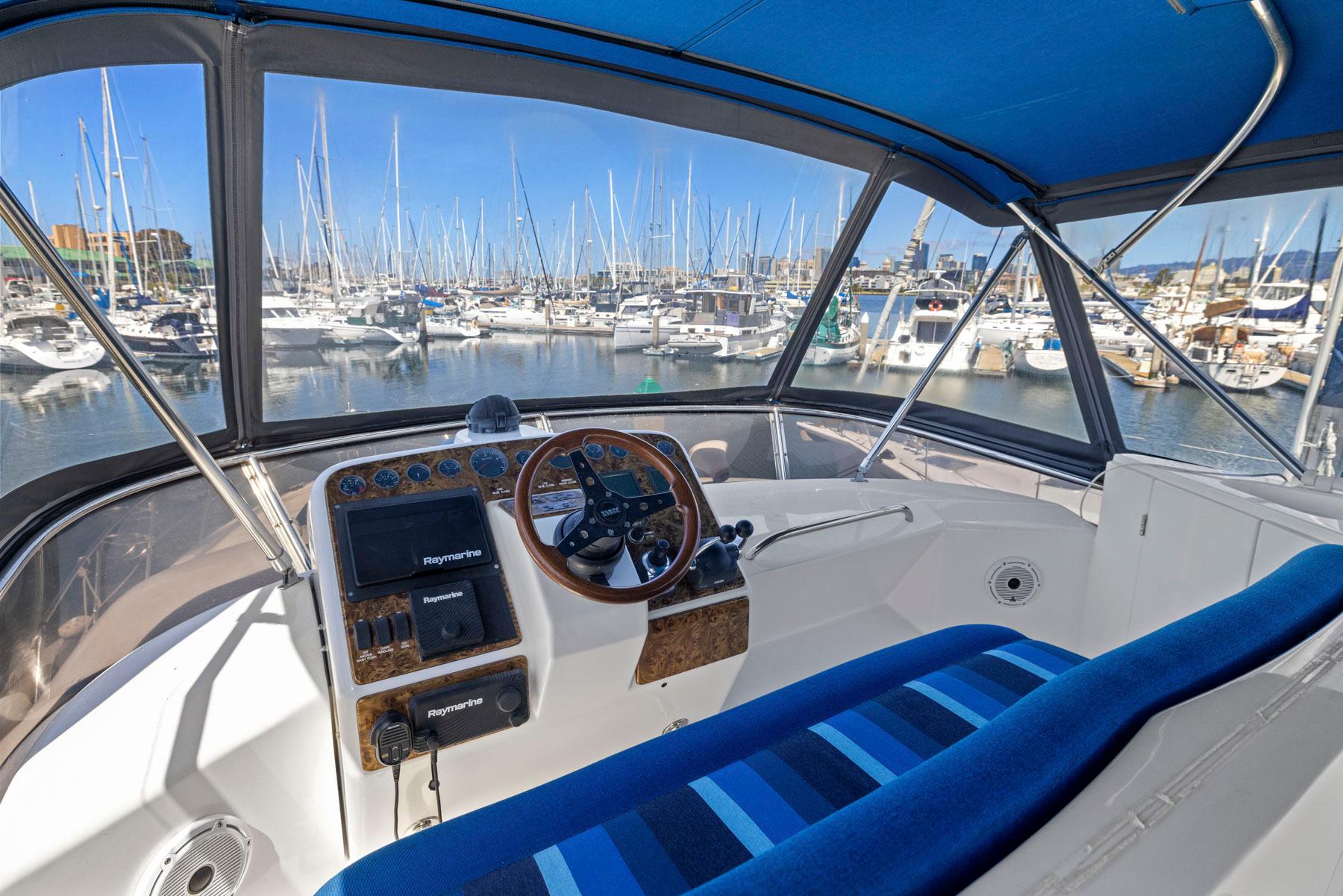Cockpit view of 2008 Dyna 51 yacht with marina background and blue-striped seating.