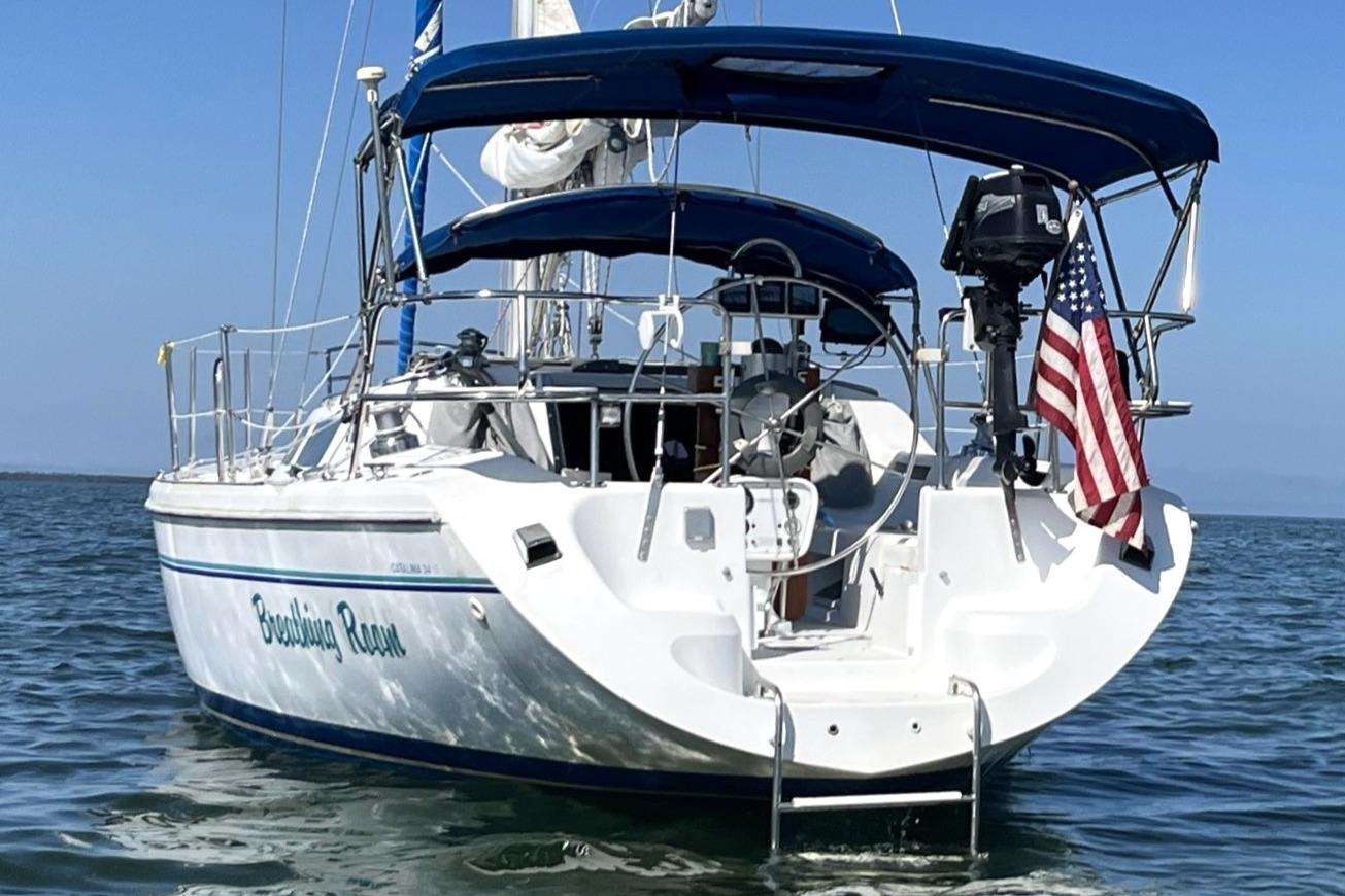 1998 Catalina 34 MkII sailboat with American flag, anchored on calm water.