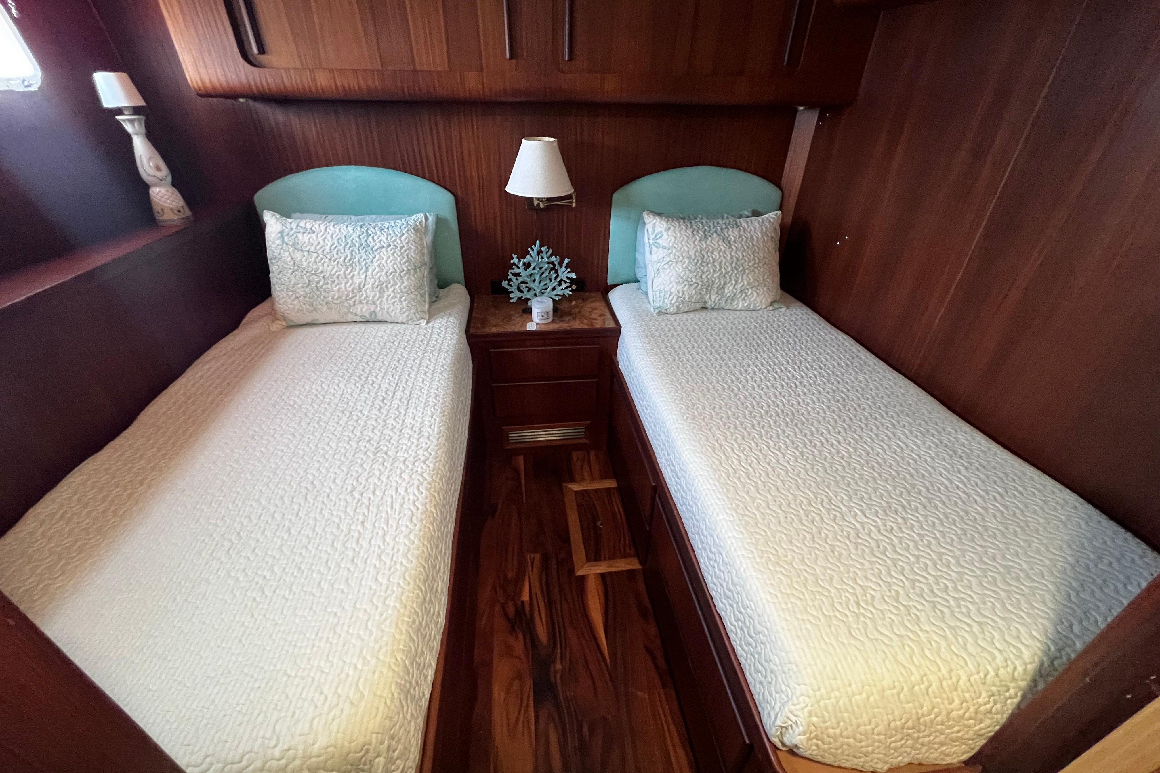 Twin beds in a 1987 Hatteras 70 Cockpit Motor Yacht cabin with elegant wood paneling.
