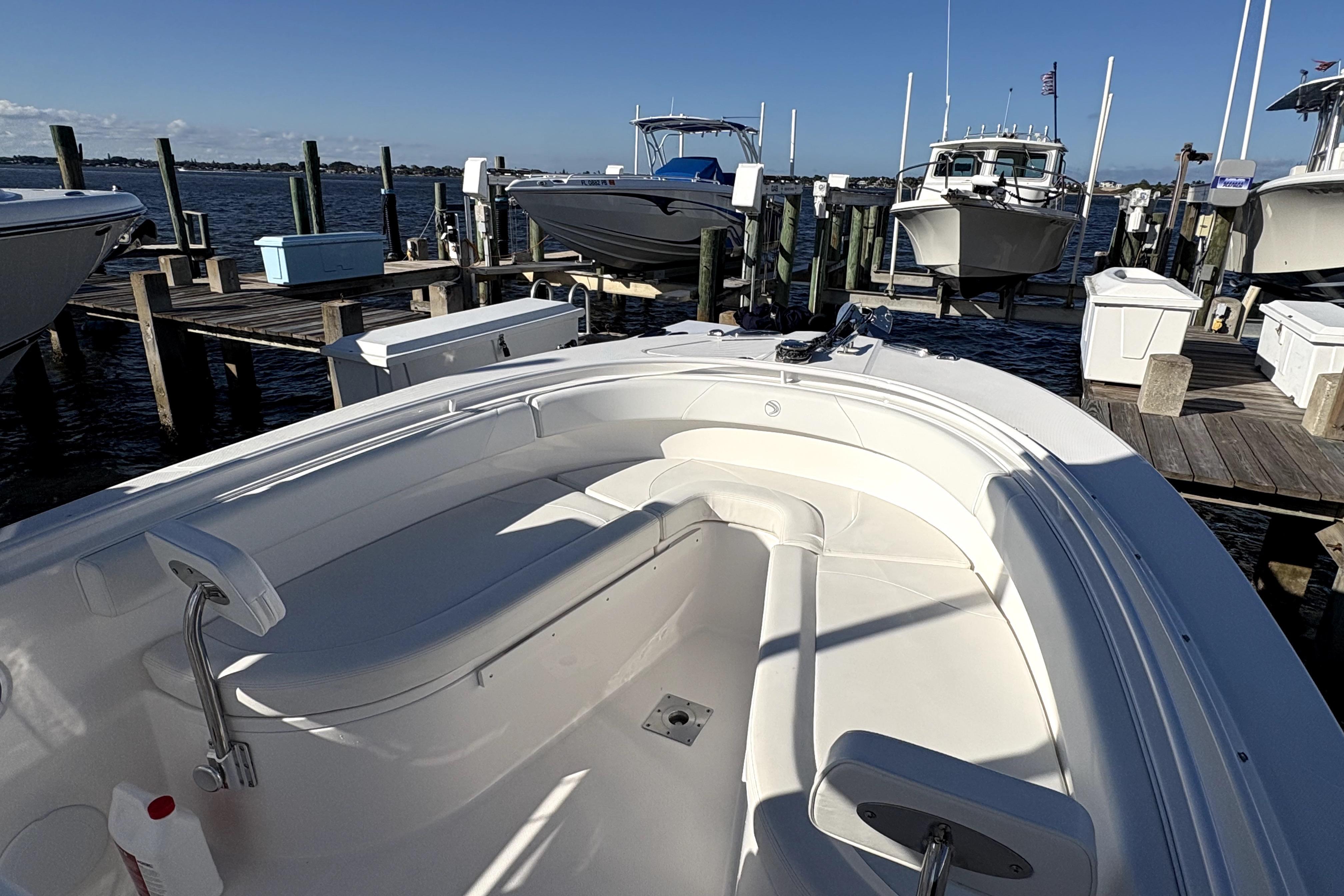 2015 Edgewater 245CC boat docked at marina, featuring spacious seating and clear skies.