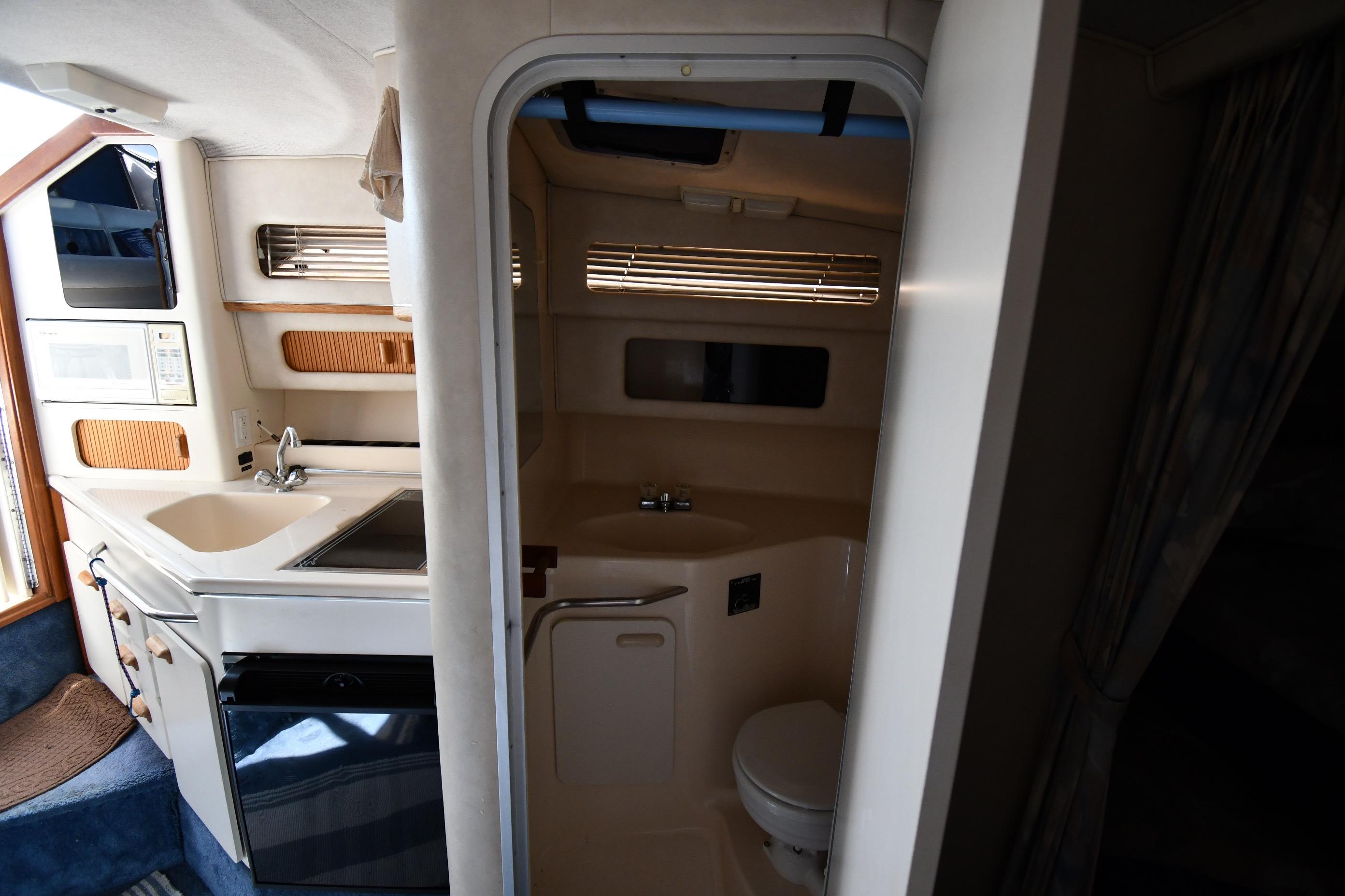 Interior of 1993 Sea Ray 300 Sundancer showing kitchenette and compact bathroom.