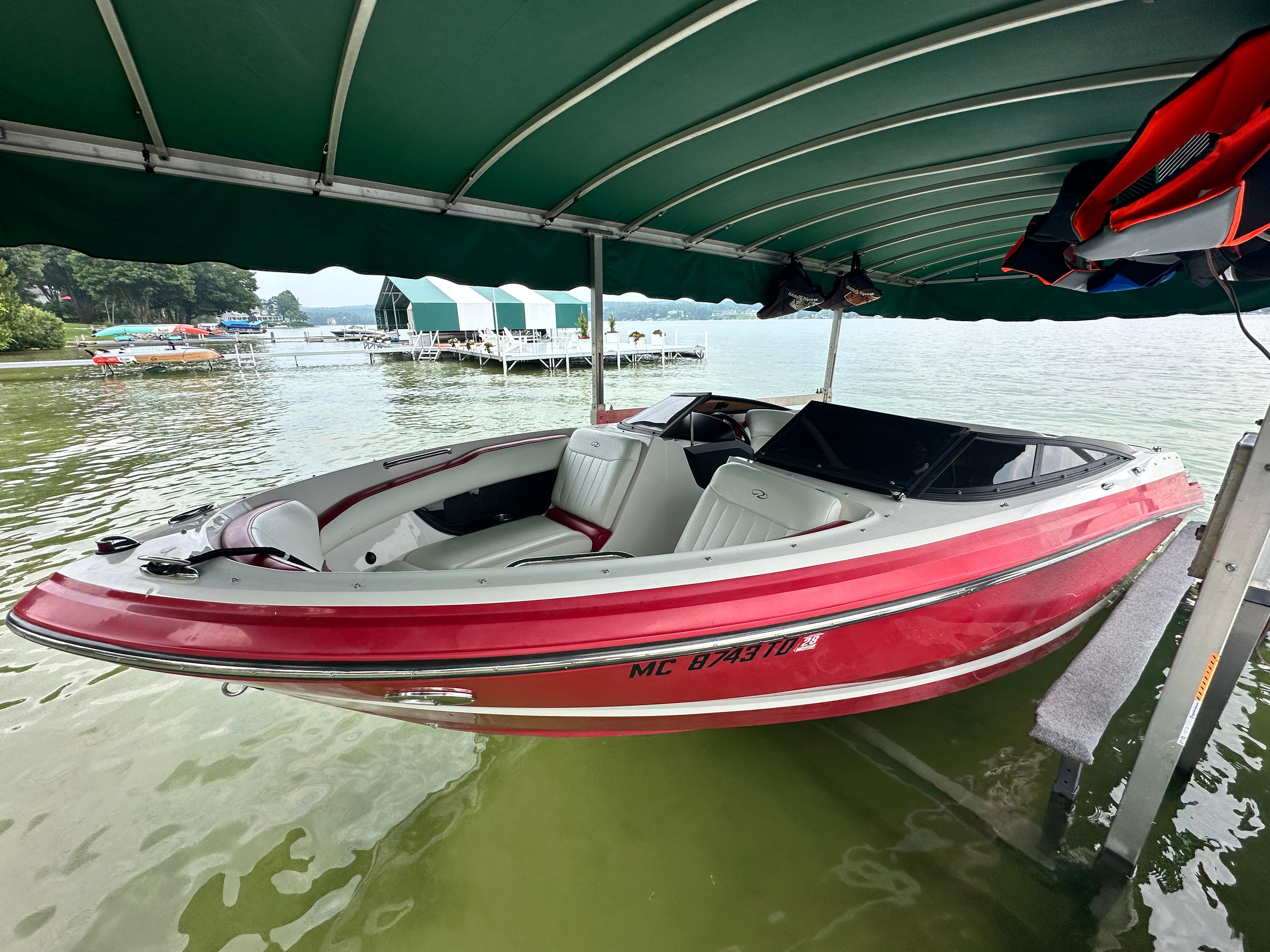 2008 Regal 2200 RS boat docked under a green canopy on a lake.