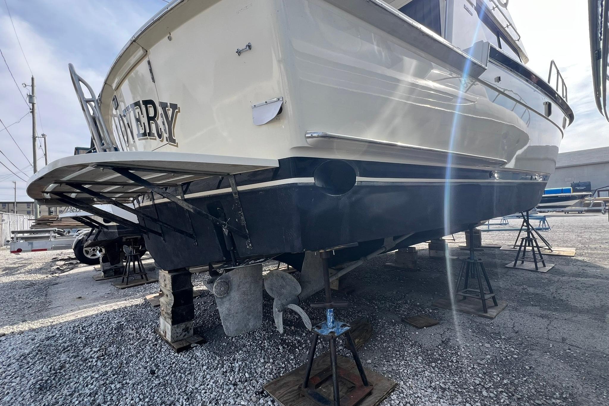 1990 Hatteras 41 Convertible boat on stands, rear view, in a boatyard.