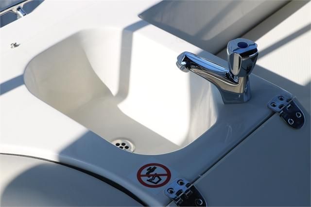 A sink with a shiny faucet on a boat, surrounded by white surfaces.