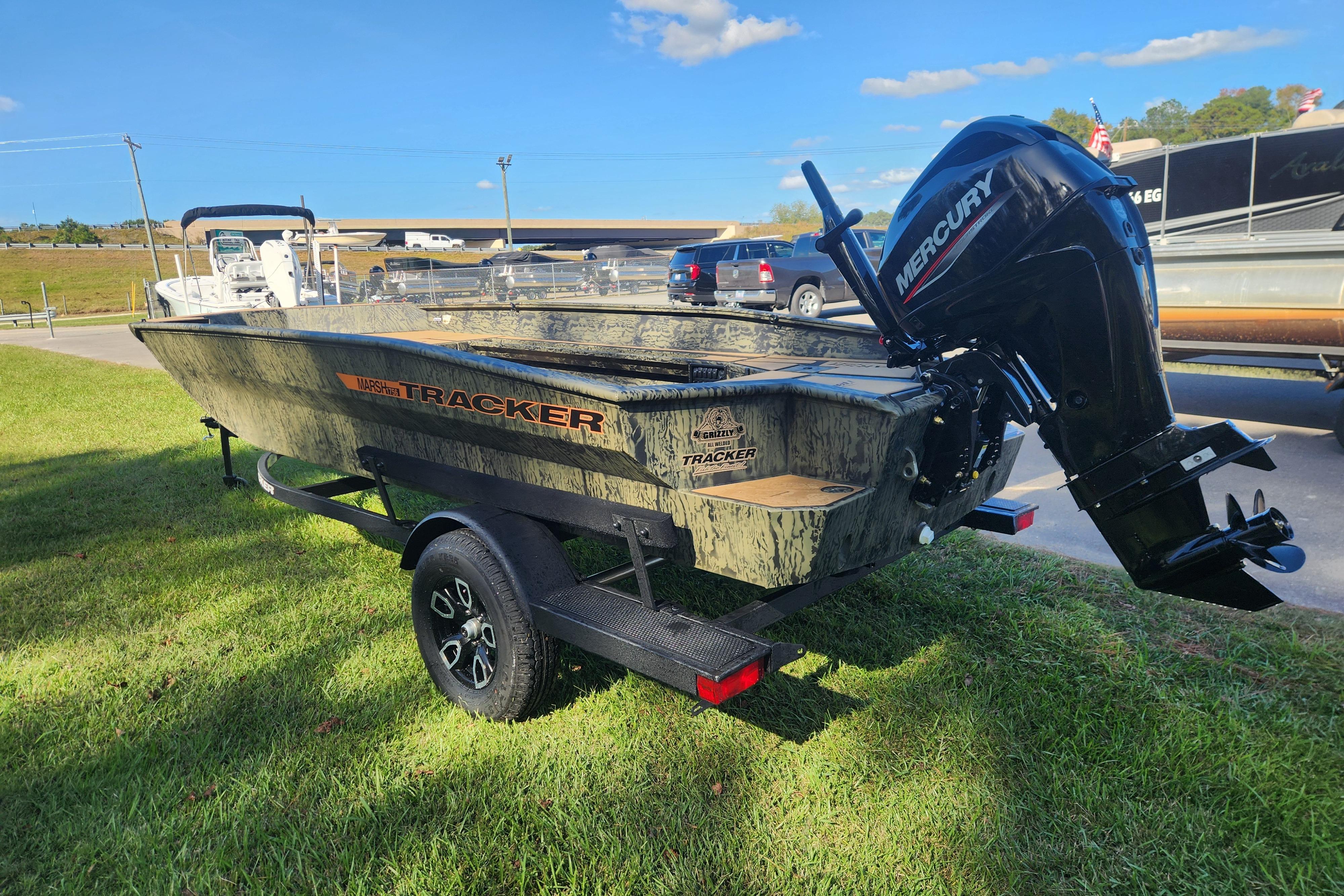 2026 Tracker Grizzly 1756 T Marsh boat with Mercury engine on trailer, parked on grass.