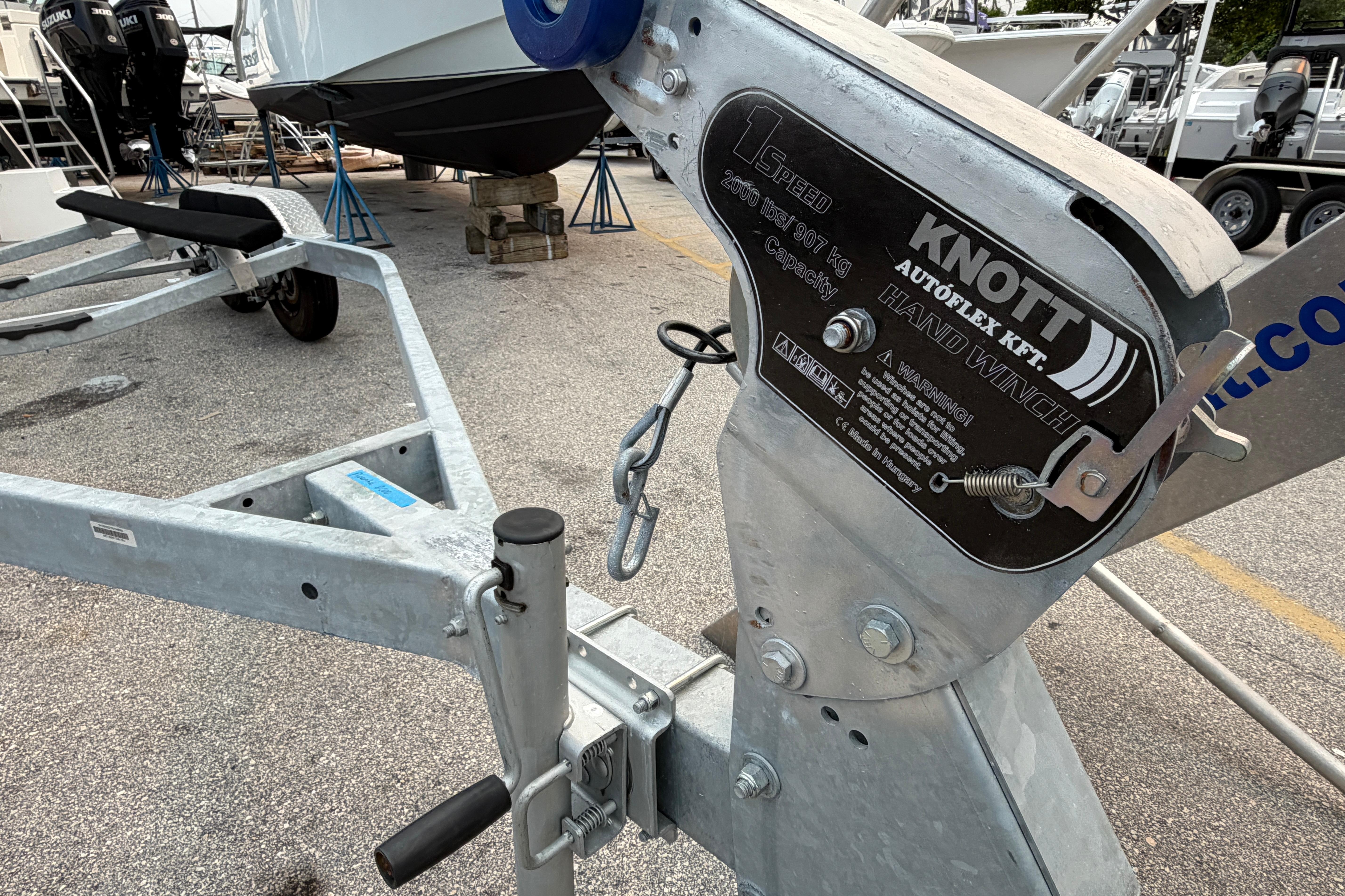 Trailer with Knott Autoflex hand winch, 2000 lbs capacity, in a boatyard setting.