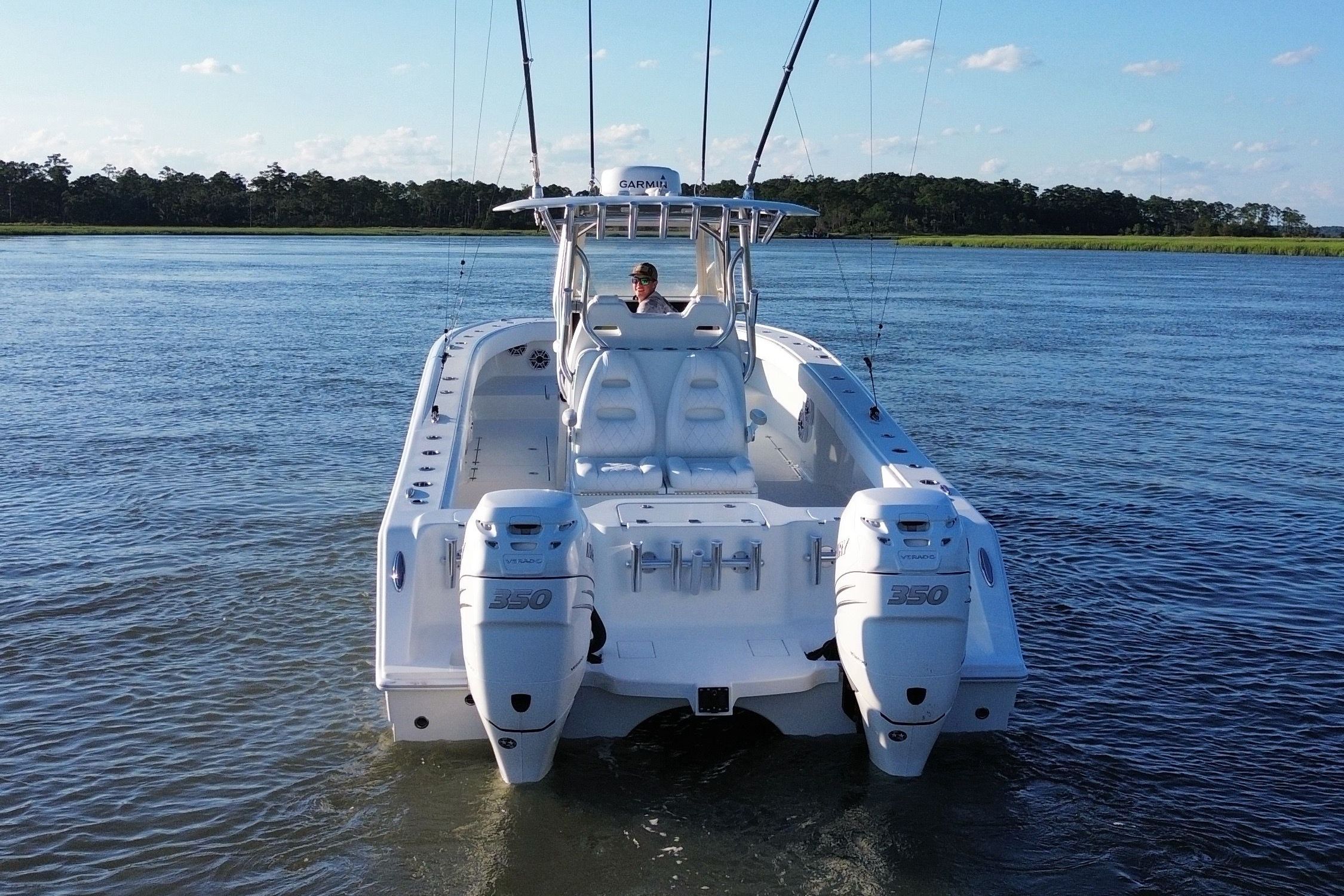 A white boat with two outboard motors navigates calm waters.