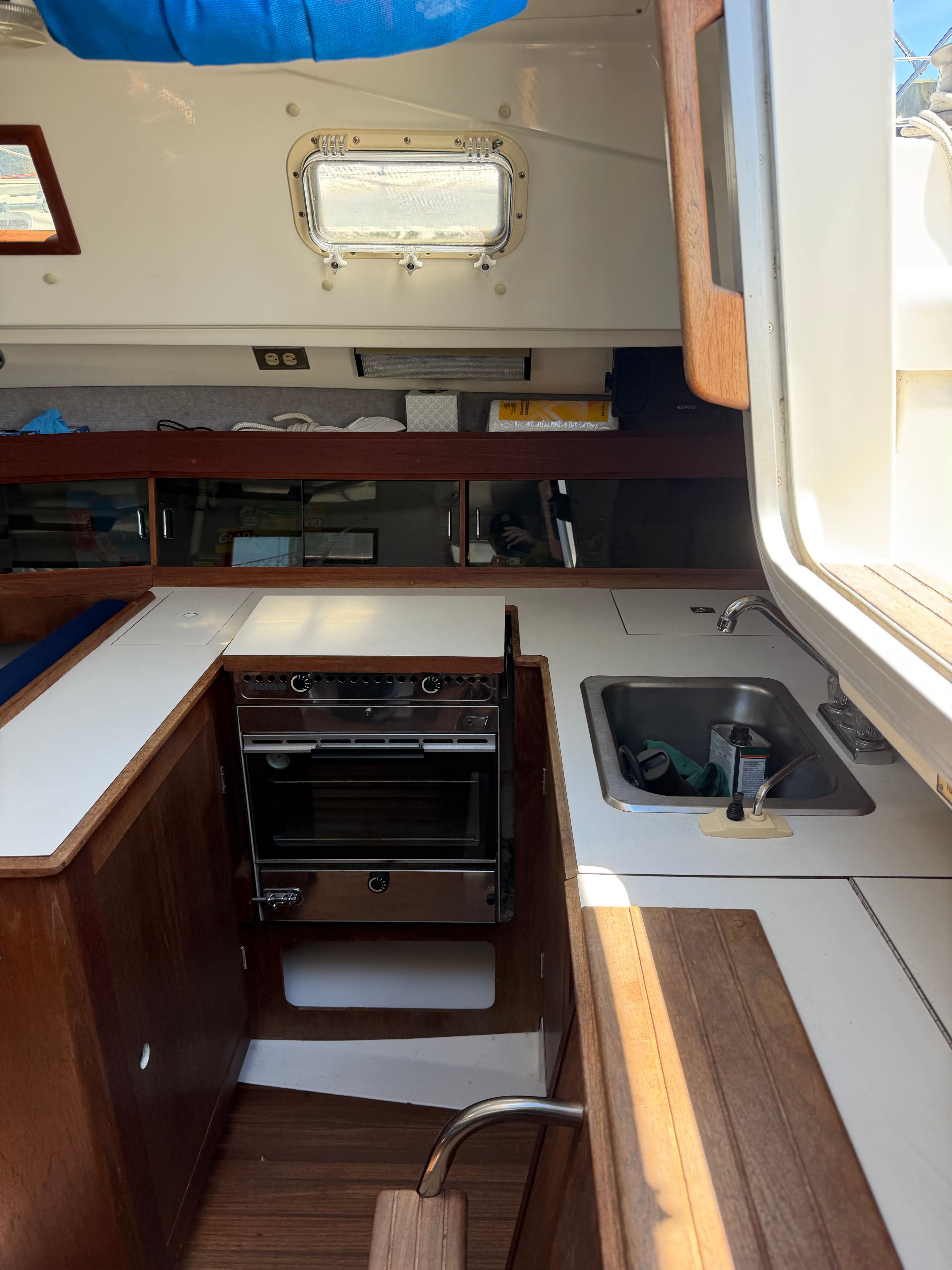 Interior of a sailboat with stove, sink, and wood paneling.