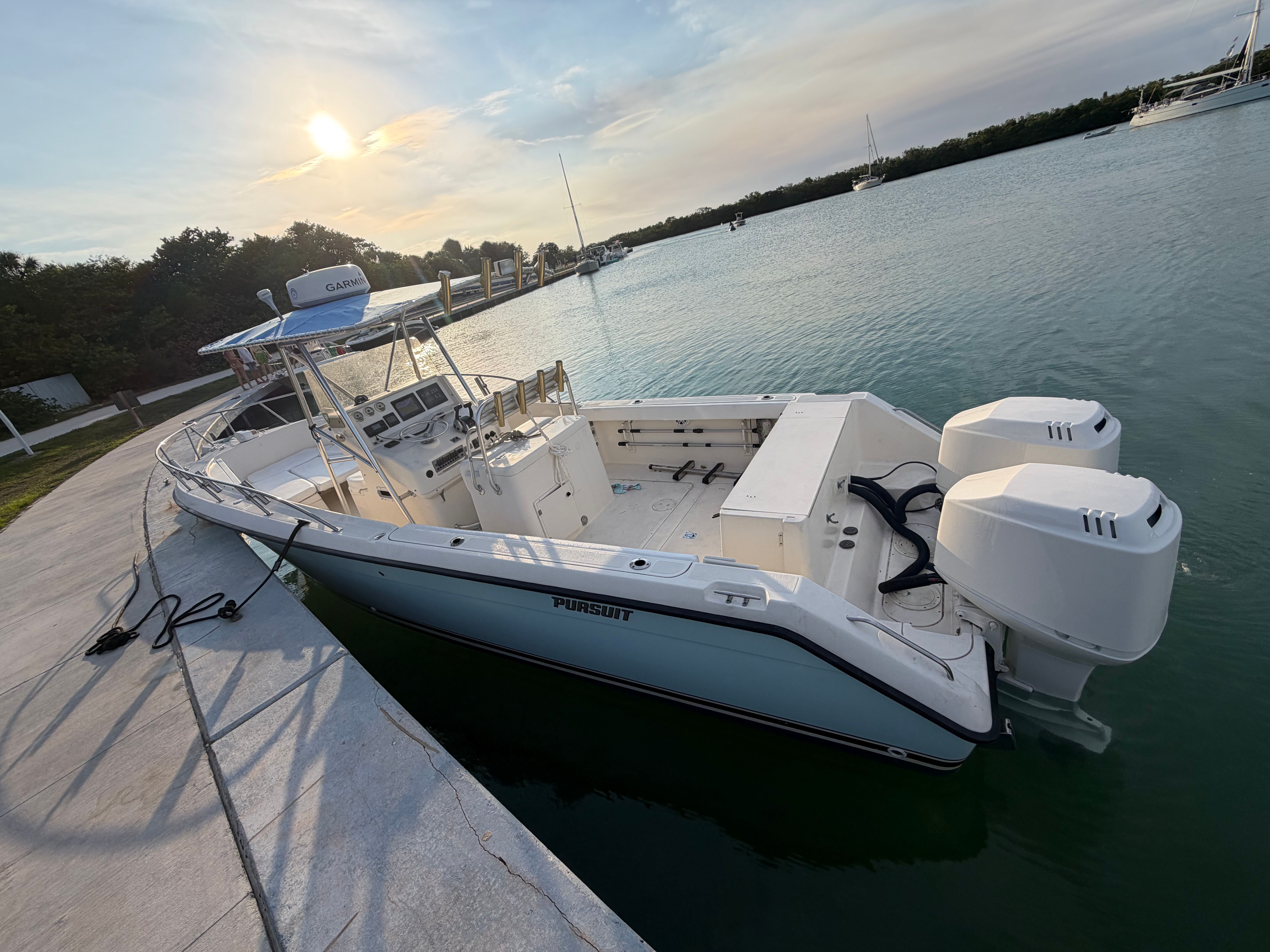 2004 Pursuit 2870 boat docked by the water at sunset.