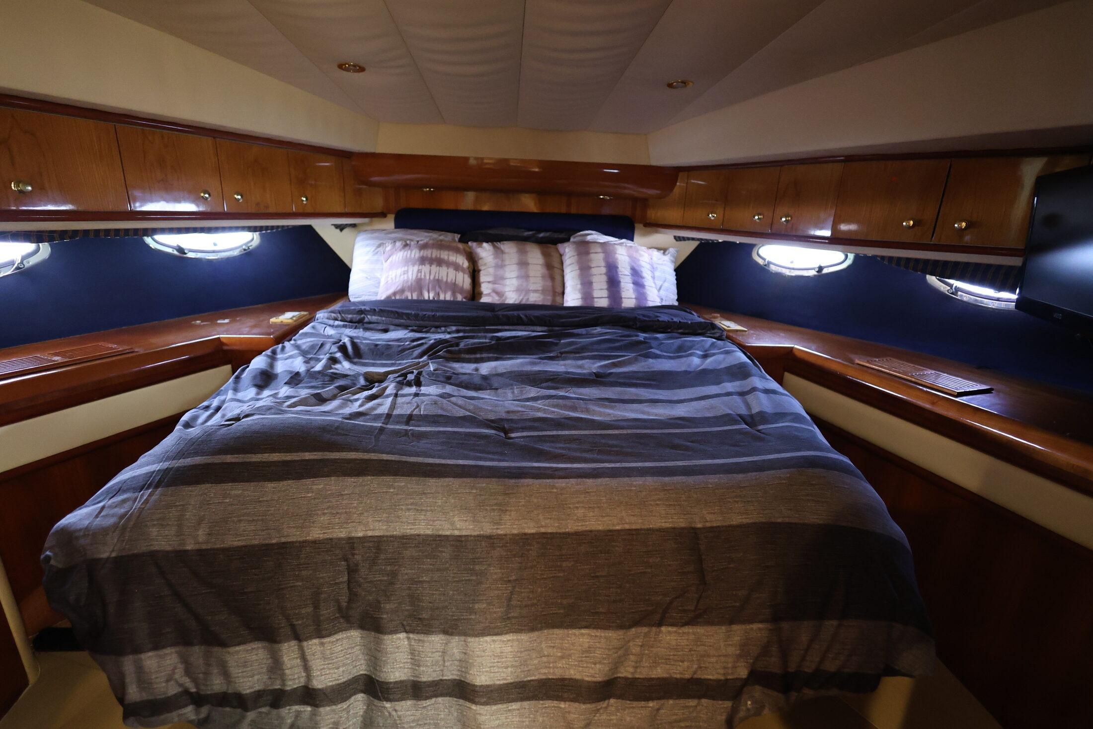 Luxurious cabin interior of 1999 Neptunus 54 Express yacht with cozy bed and wooden cabinetry.