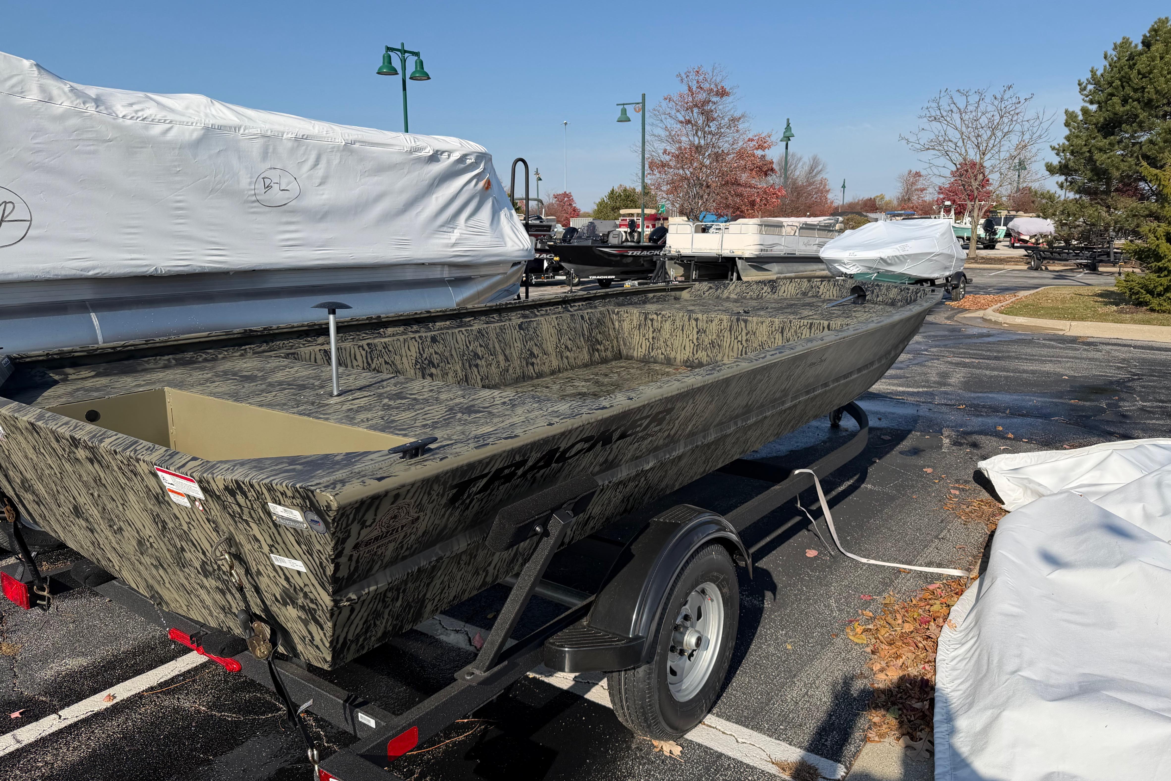 2026 Tracker Grizzly 1860 Utility boat on trailer in parking lot.